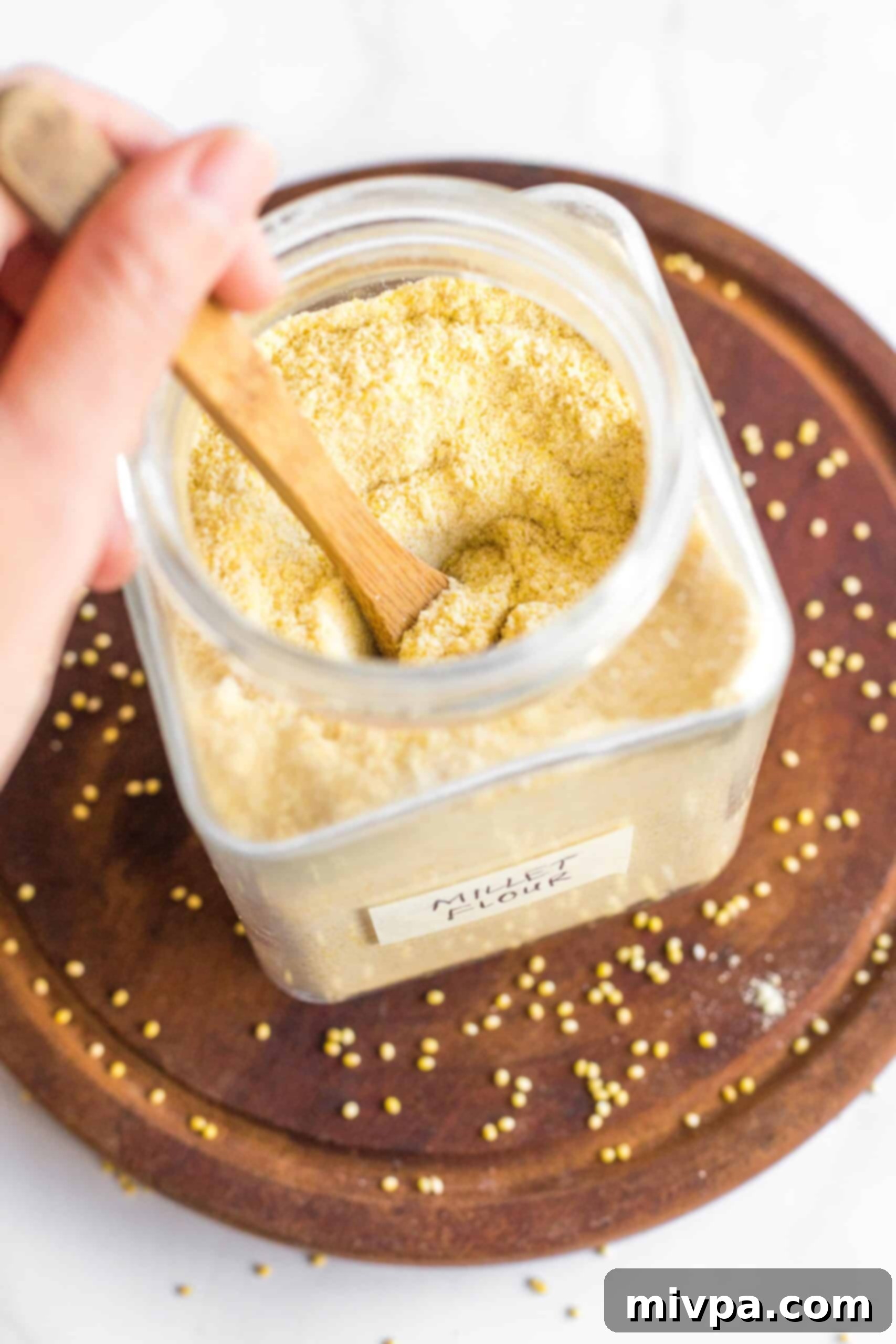 Mixing freshly made millet flour in a glass jar.