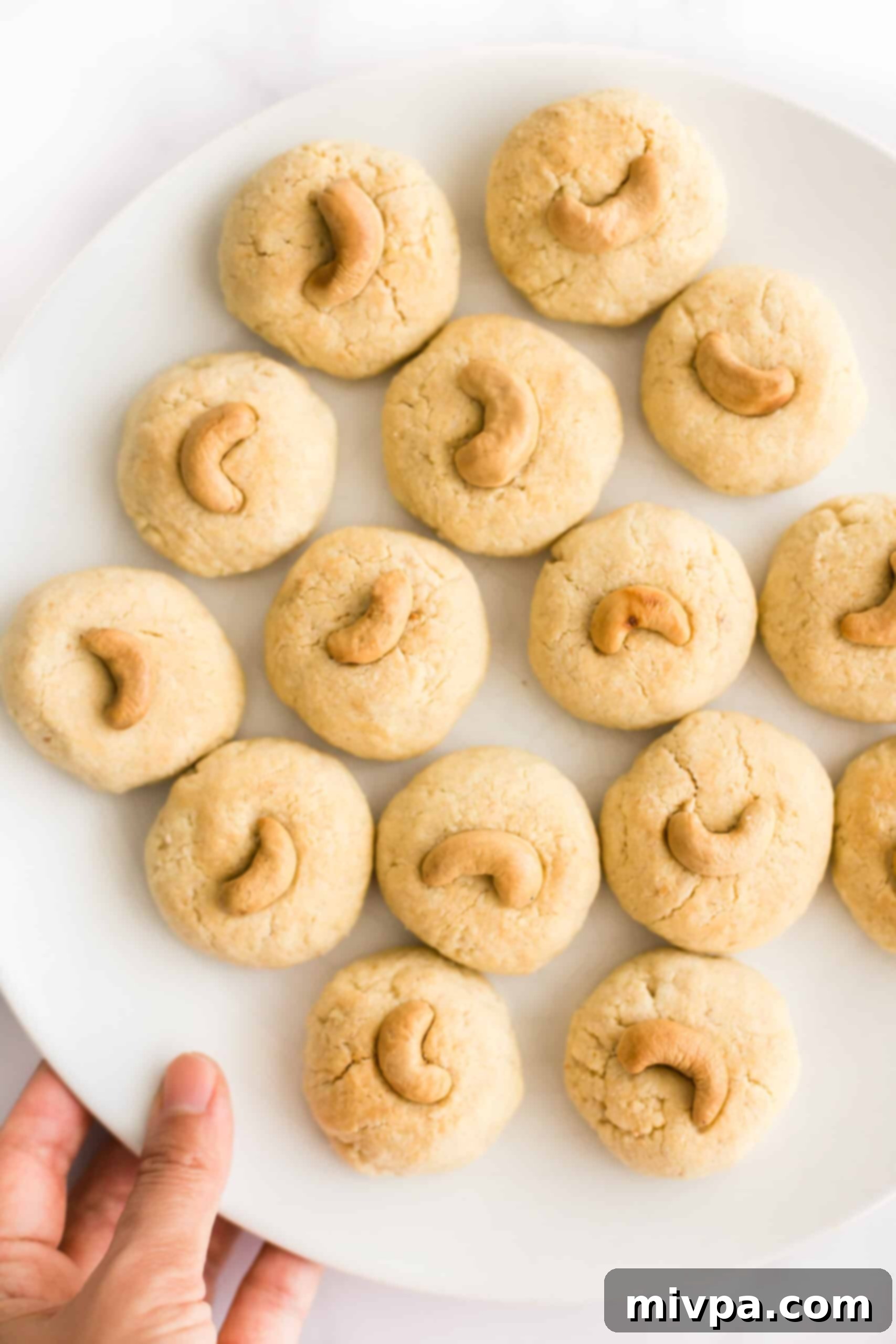 Easy Cashew Nut Cookies (Gluten-Free, Dairy-Free) - A festive treat for any celebration Holding a plate of gluten-free cashew nut cookies, showcasing their golden-brown perfection and cashew topping.