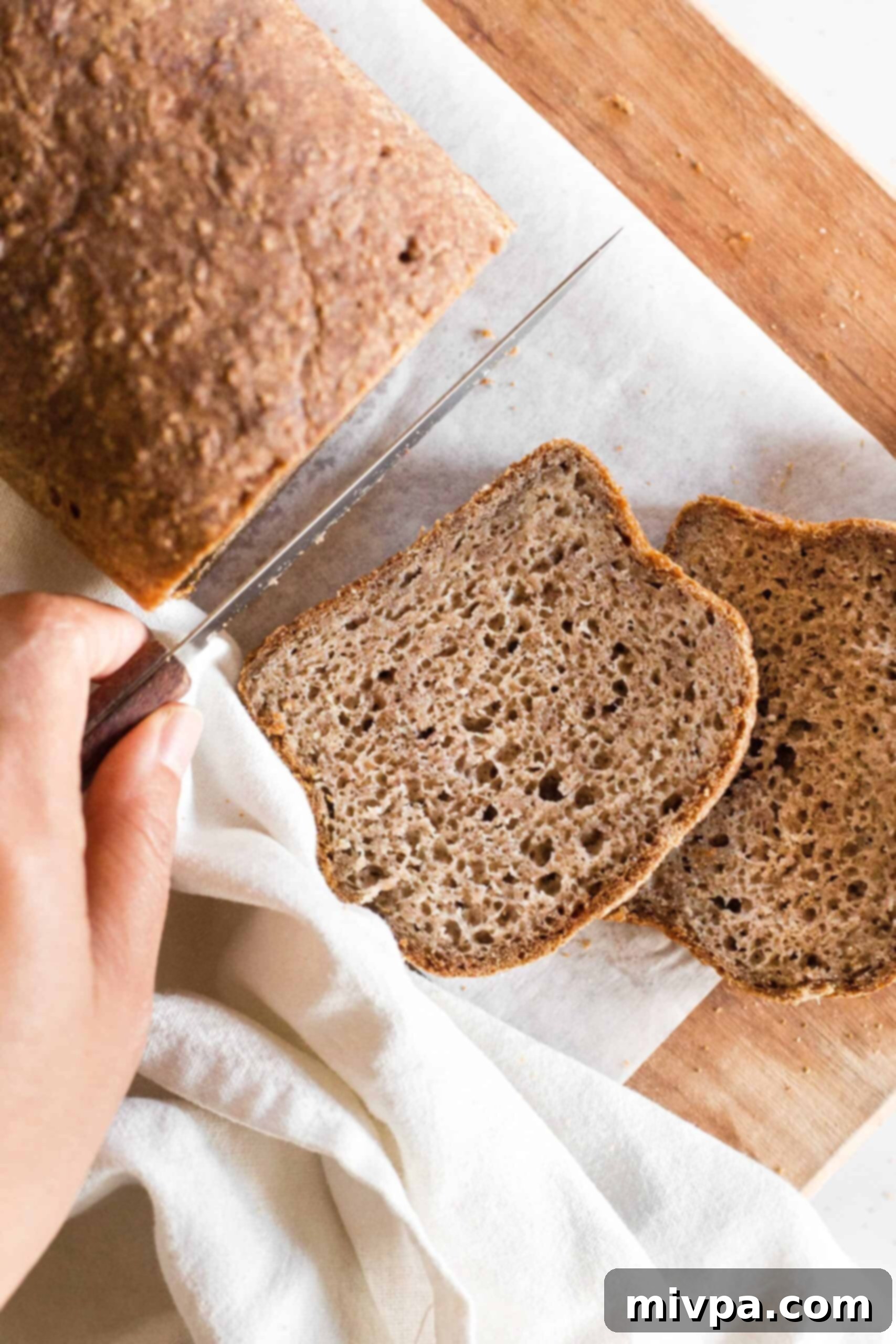 Soft, Fluffy Teff Bread (Gluten-Free, Dairy-Free) Slicing into freshly baked loaf of gluten-free teff bread.