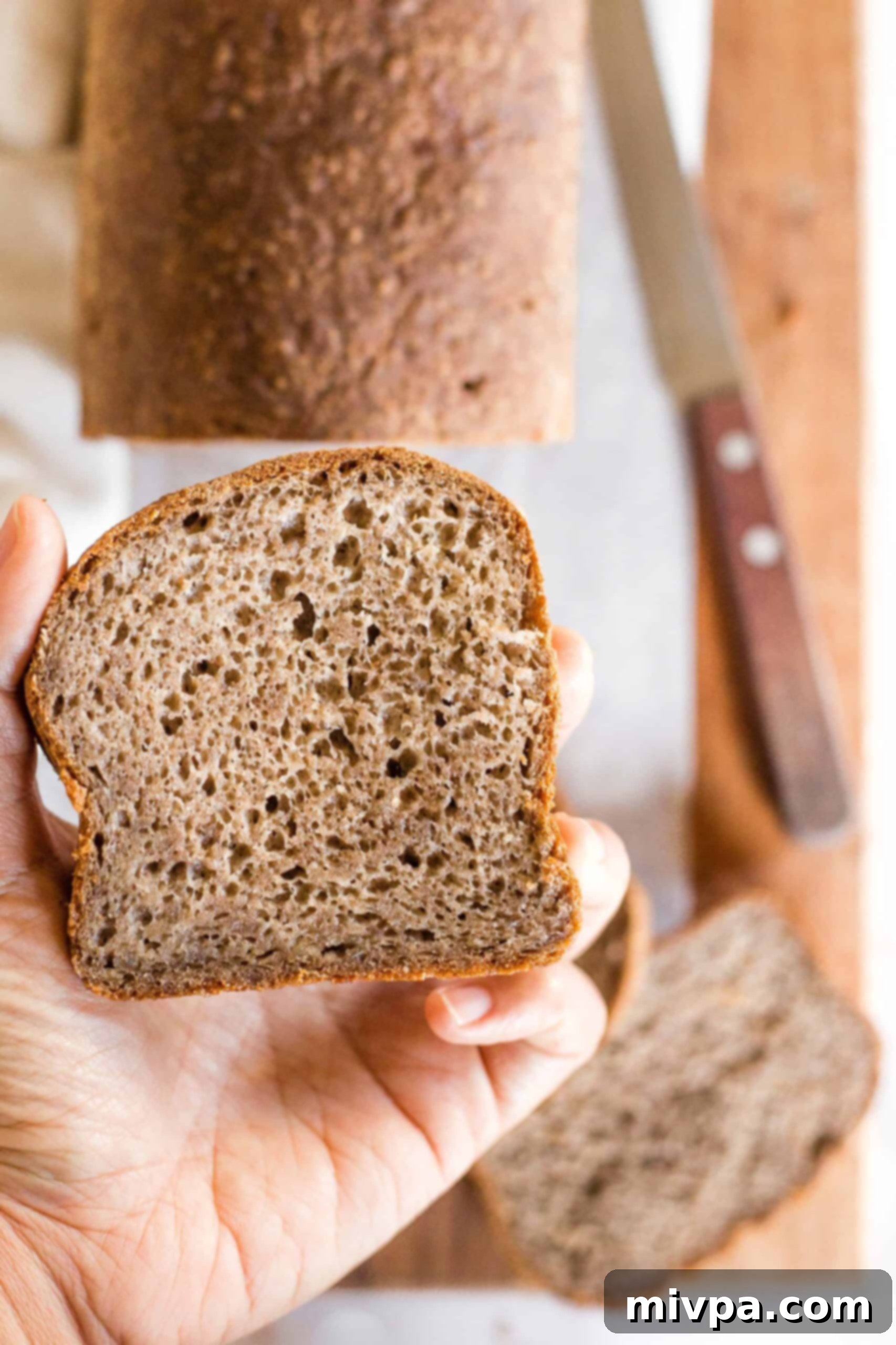 Soft, Fluffy Teff Bread (Gluten-Free, Dairy-Free) Holding up a slice of teff flour bread.