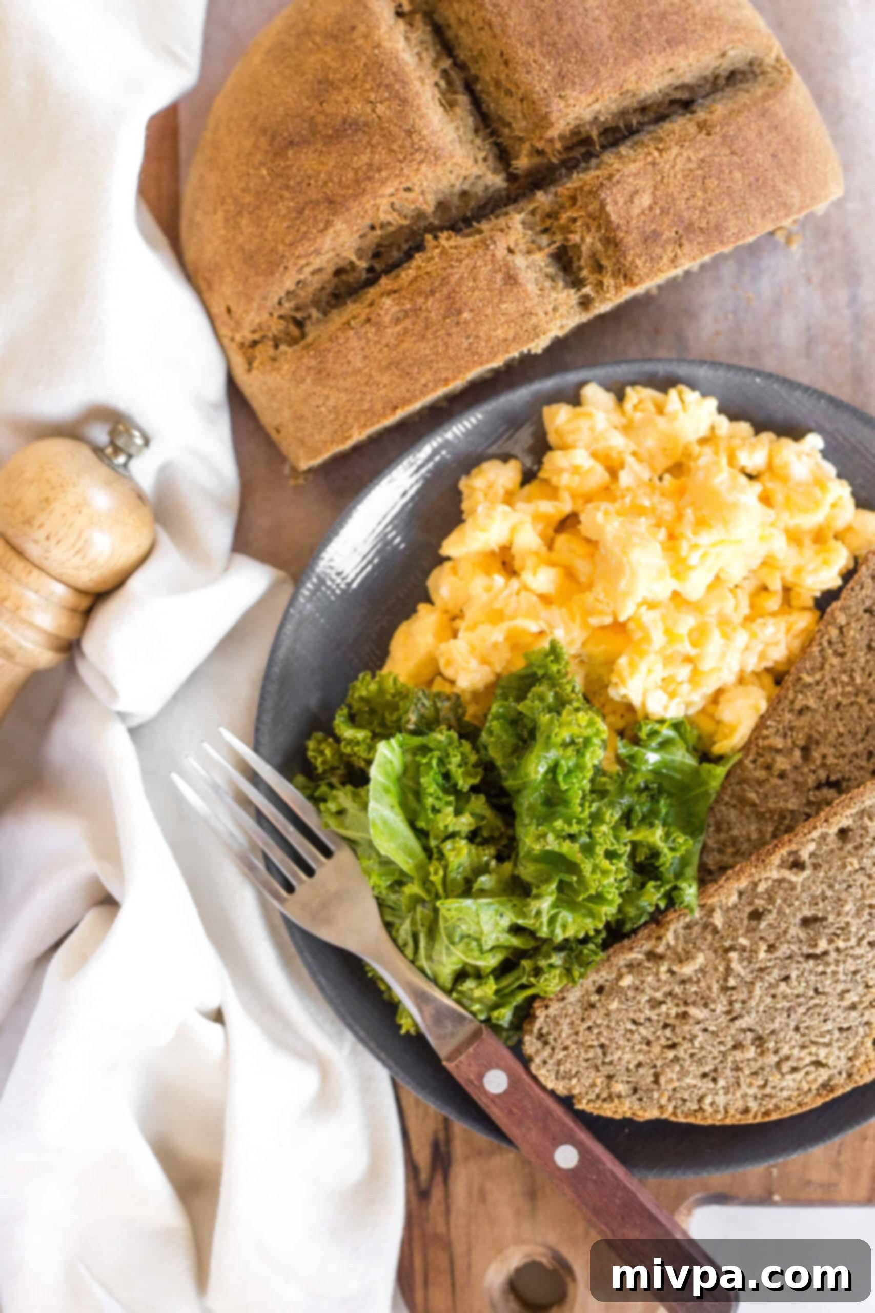 A plate of sautéed kale, scrambled eggs and two slices of Irish brown bread.
