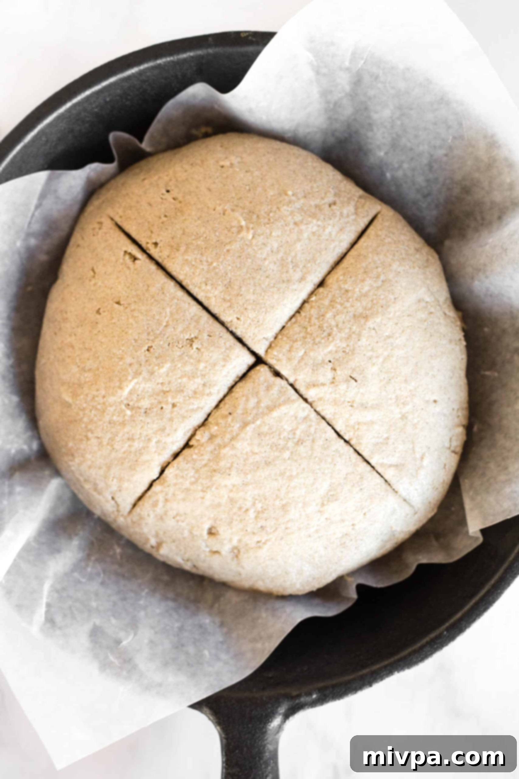 A cross cut on top of brown soda bread dough