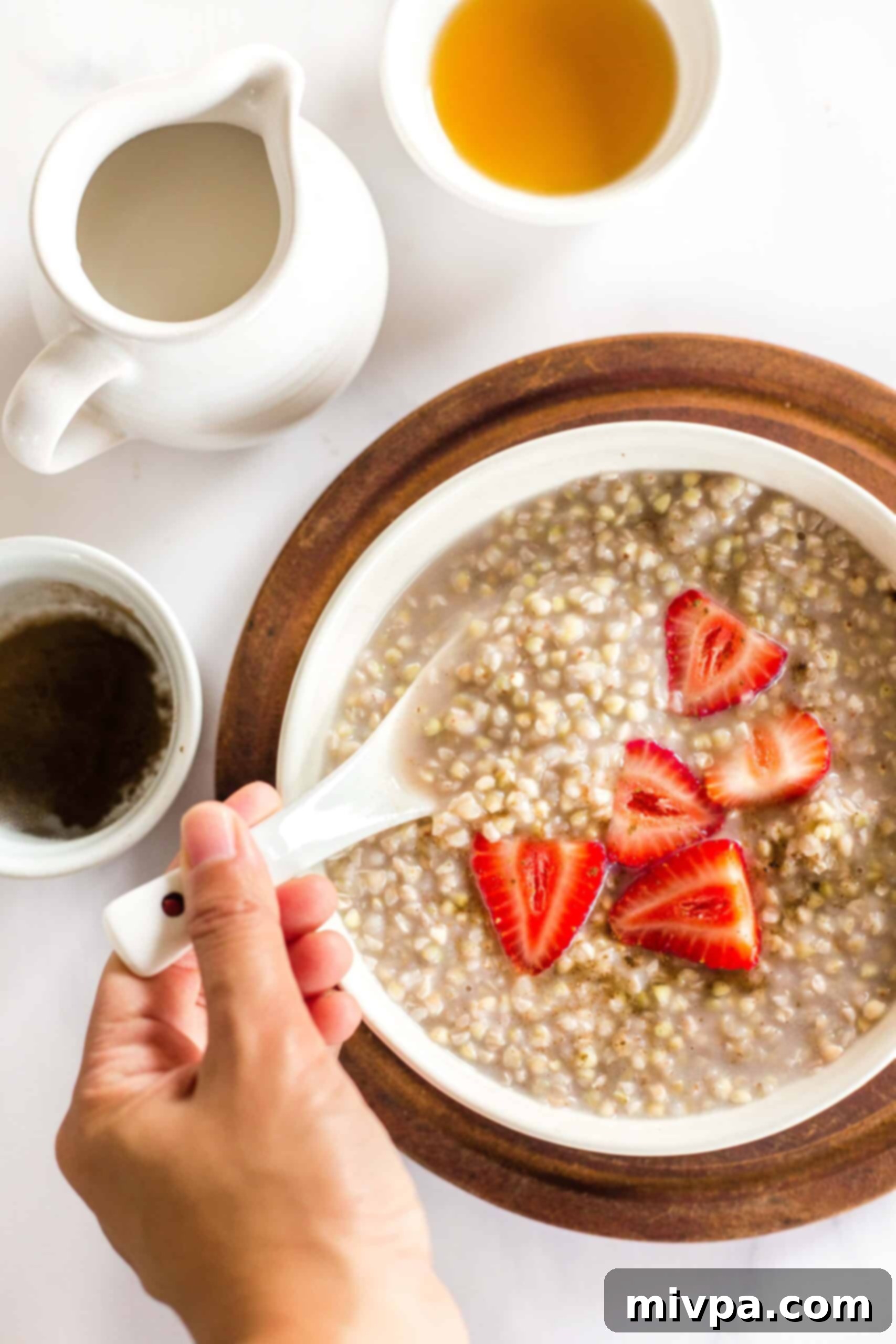 Easy Buckwheat Porridge (Gluten-Free, Vegan) Reaching into a bowl of buckwheat porridge and fresh fruit.