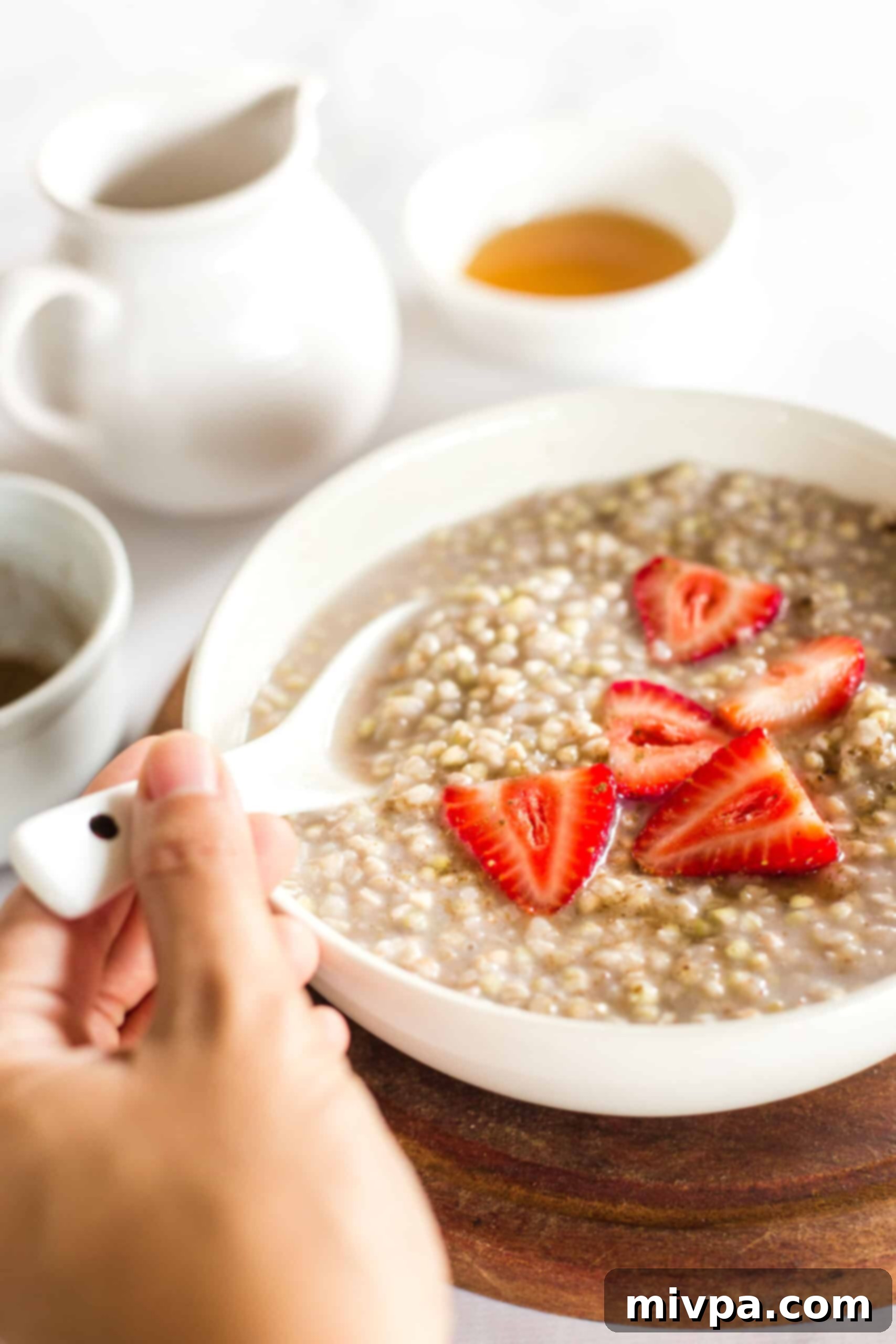 Easy Buckwheat Porridge (Gluten-Free, Vegan) Reaching for a spoonful of buckwheat porridge and strawberries.