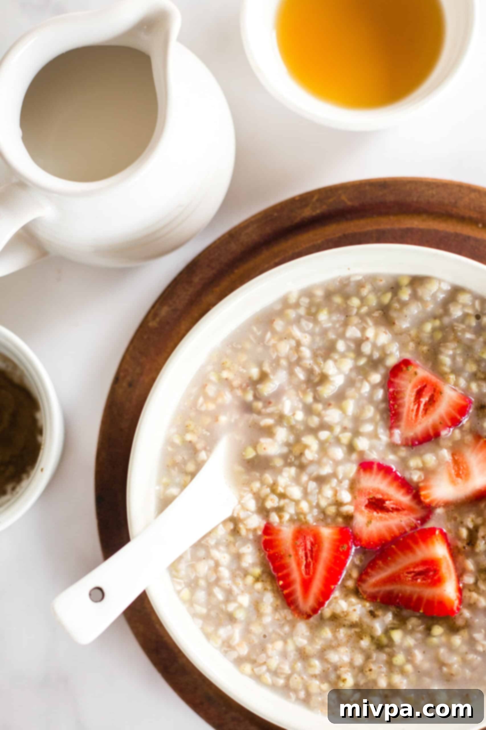 Easy Buckwheat Porridge (Gluten-Free, Vegan) A bowl of strawberries and buckwheat porridge on a wooden board.