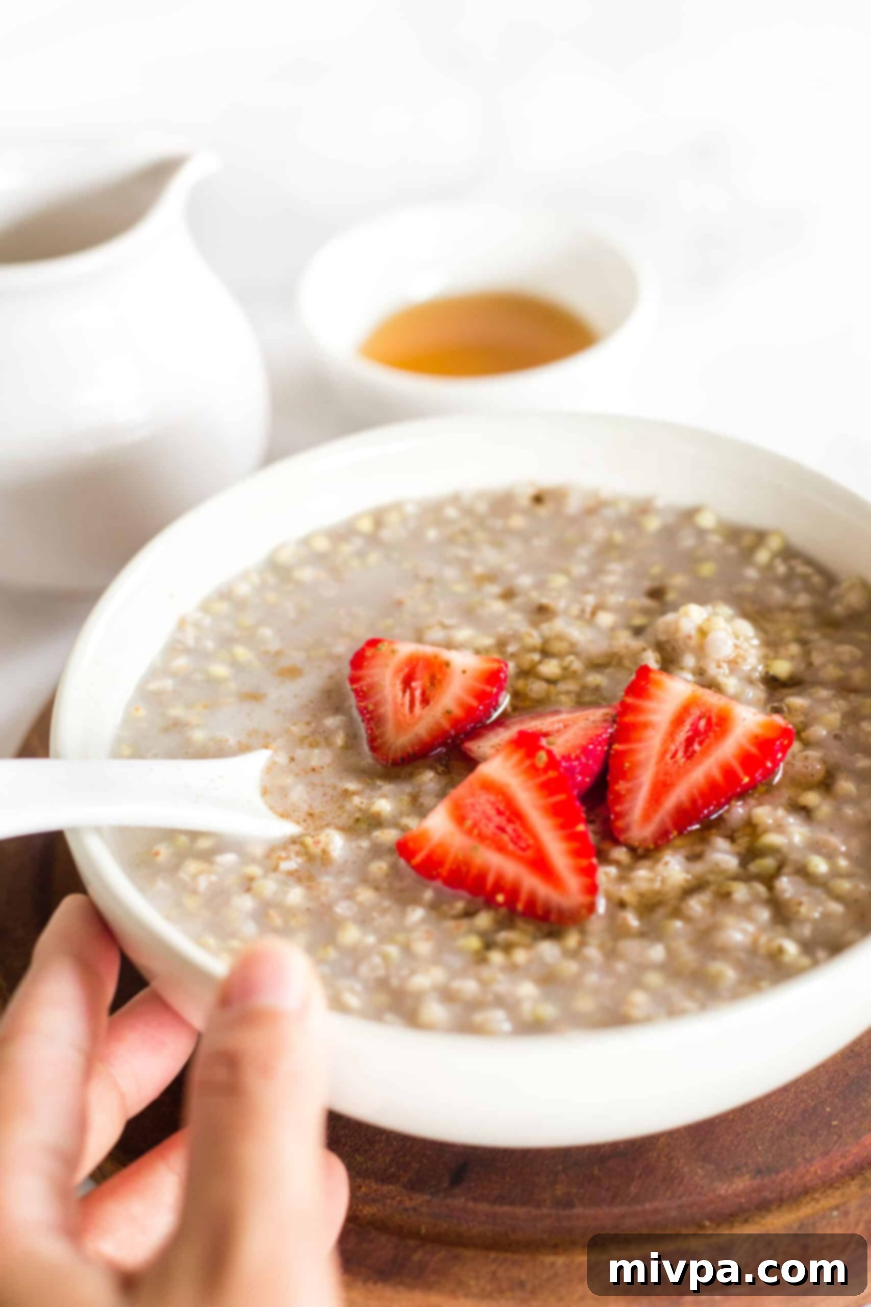 Nourishing Gluten Free Vegan Buckwheat Porridge 2 Hand holding a bowl of buckwheat porridge with fresh berries.