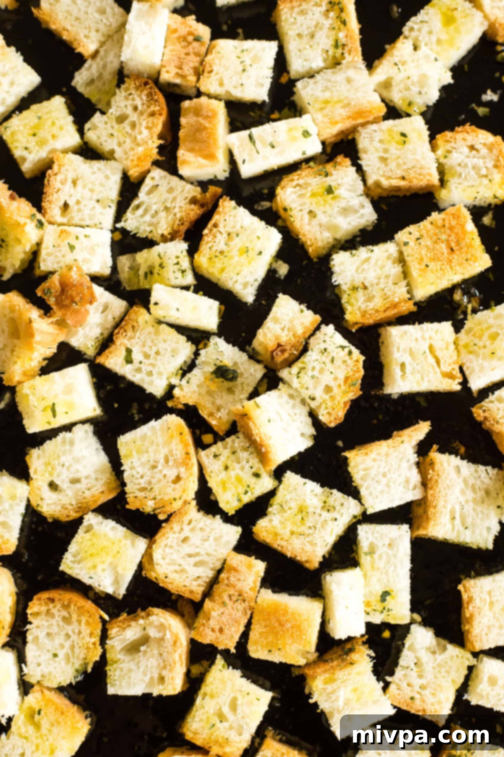 Gluten-free croutons spread out on a baking sheet, golden and perfectly toasted.