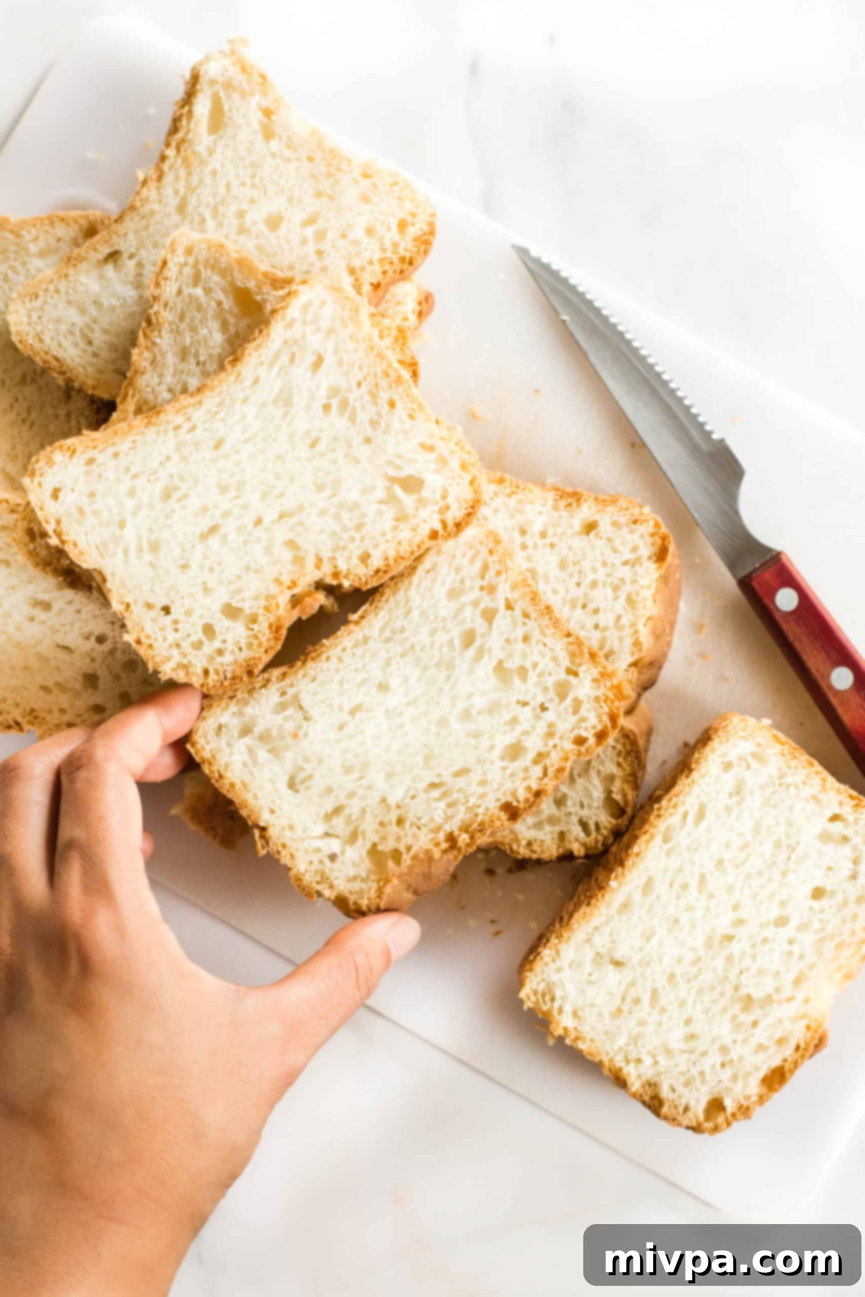 Slices of gluten-free bread laid out on a chopping board with a knife, ready for cubing.