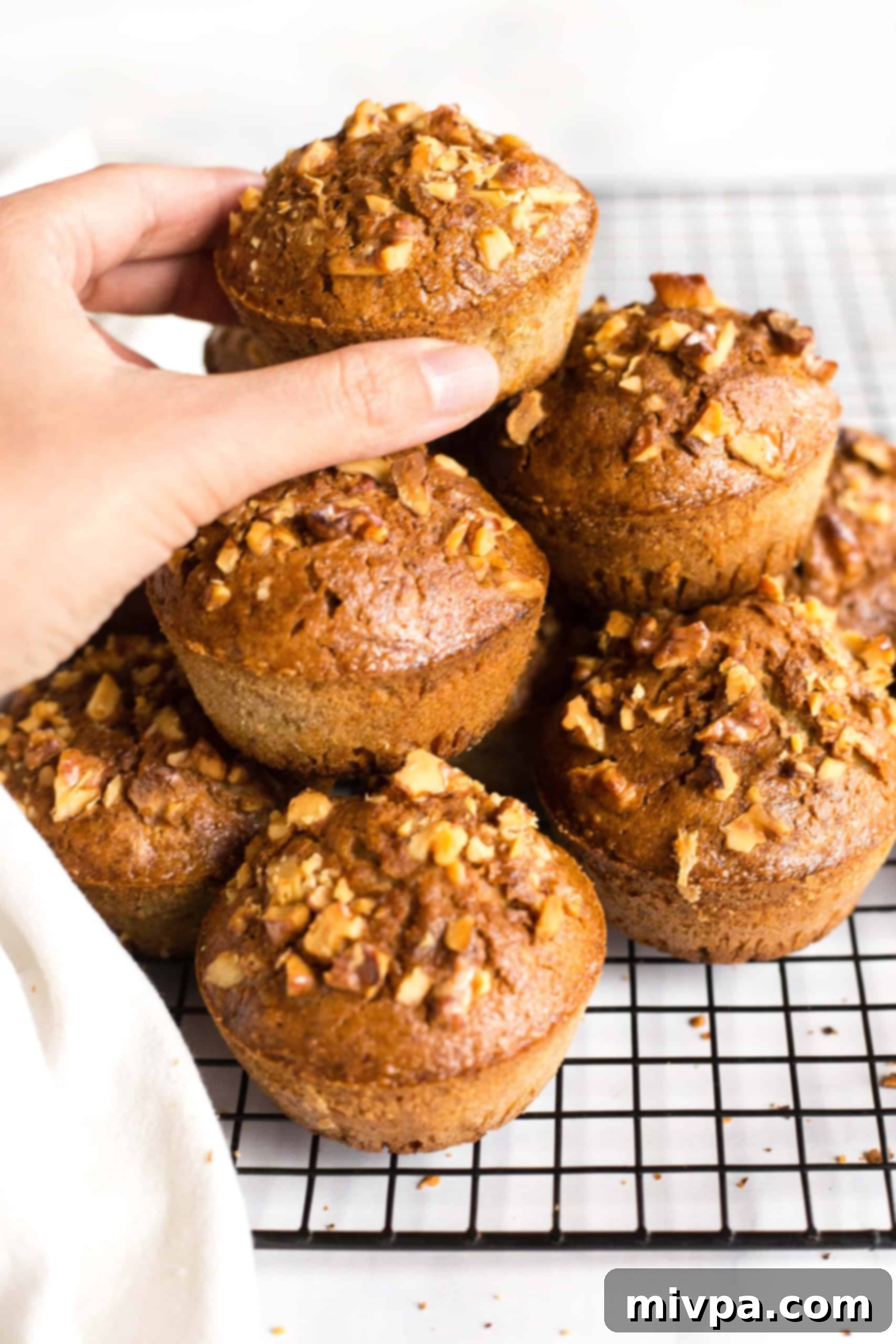 Reaching for a muffin from a stack of gluten-free zucchini muffins.