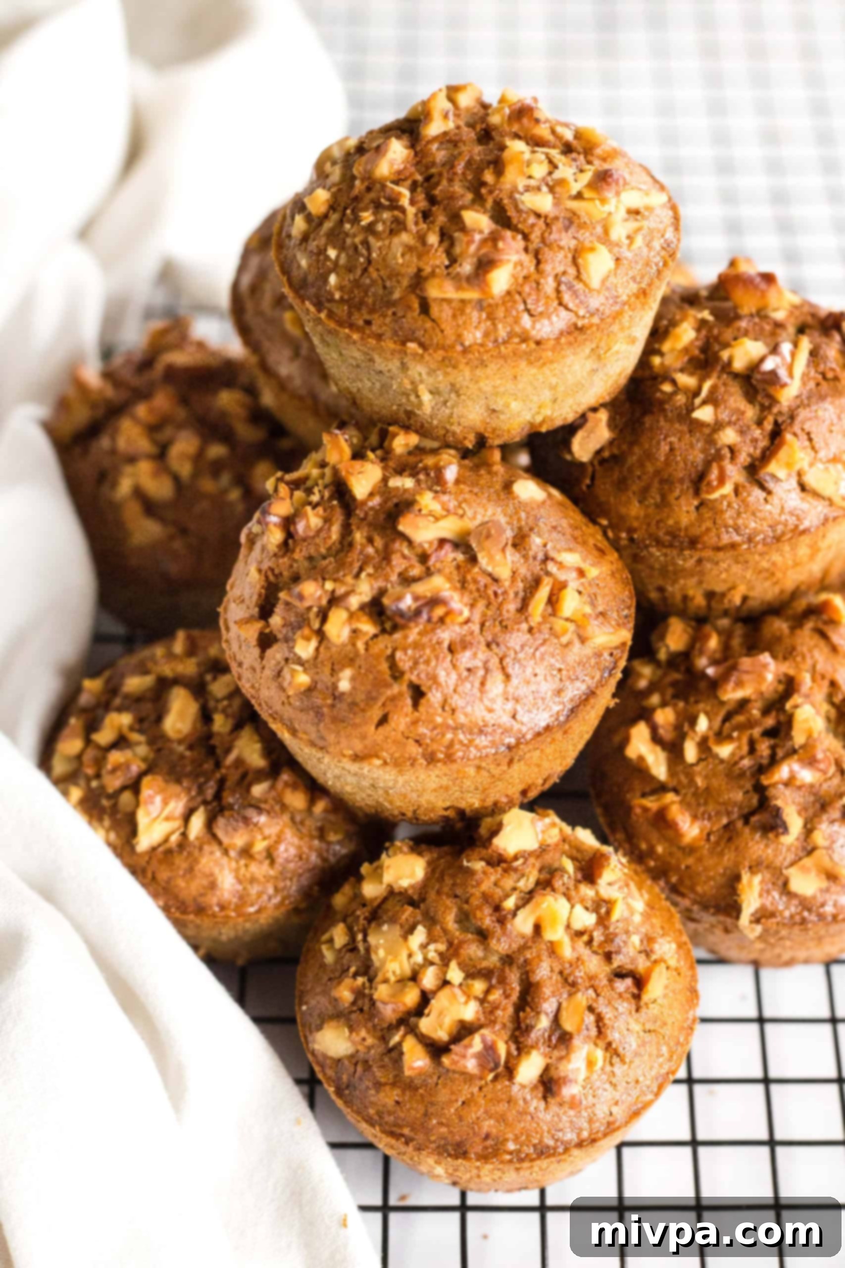 A stack of walnut-studded gluten-free muffins on wire rack.