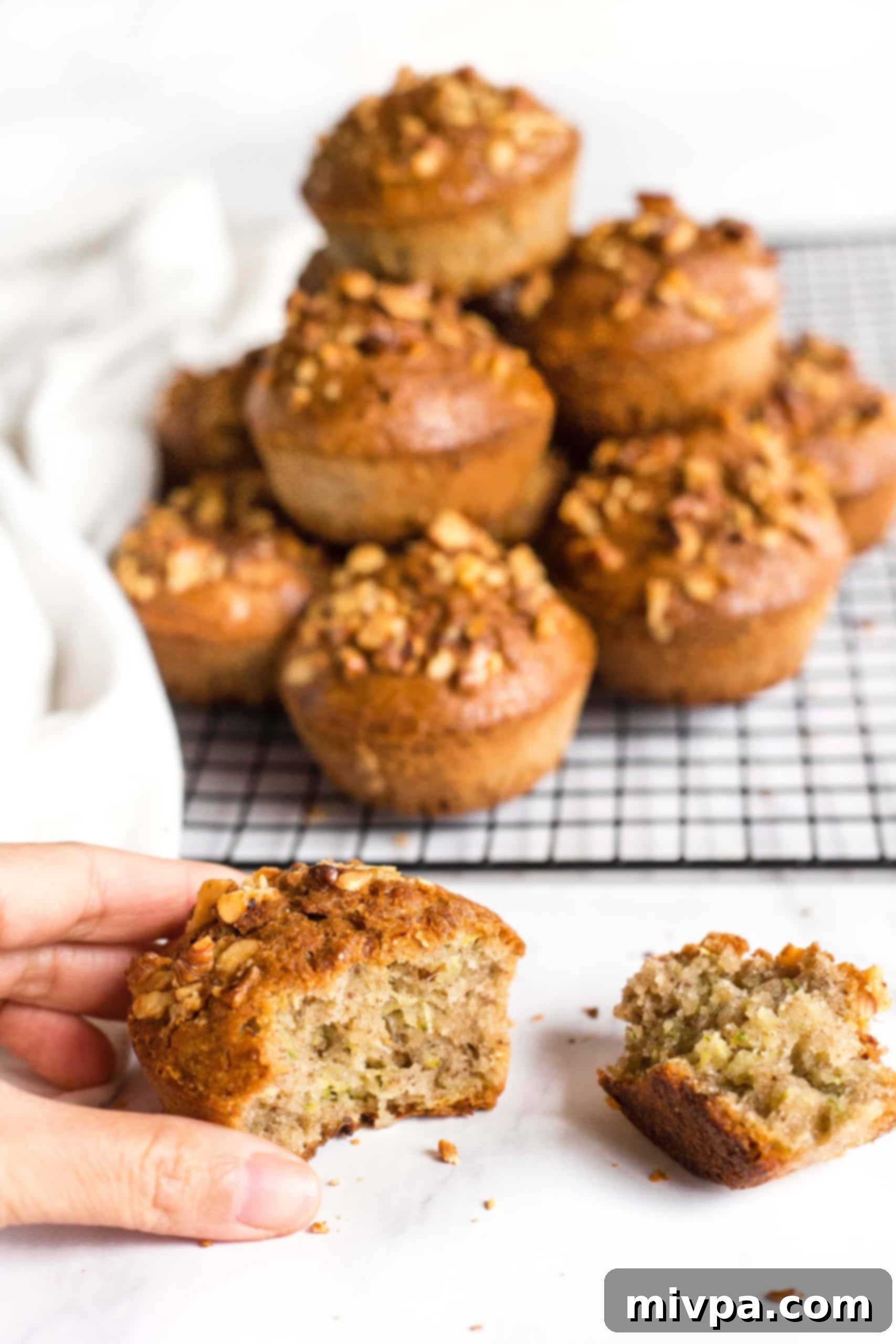 Hand holding a half-eaten zucchini muffin.