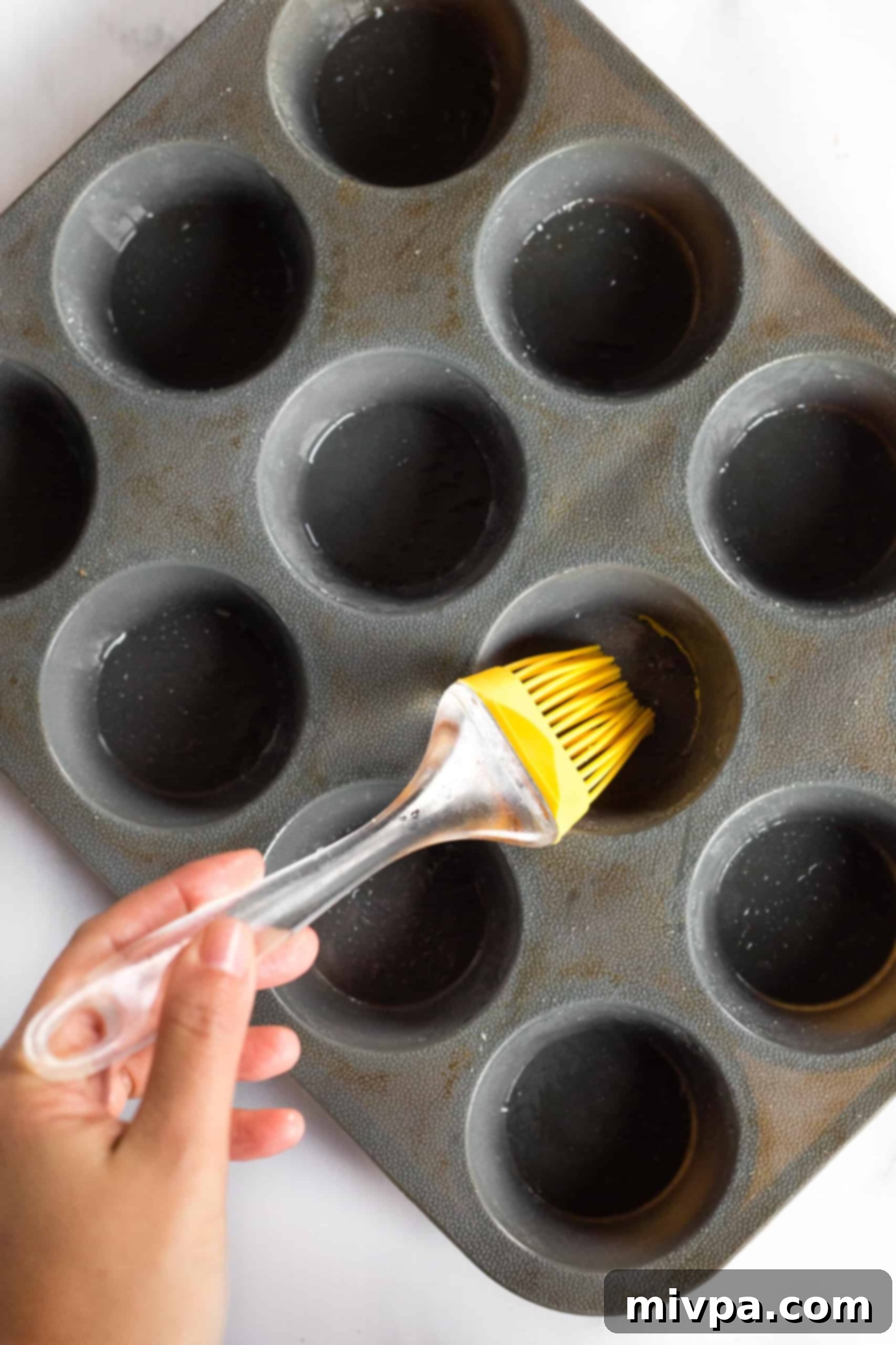 Using a yellow brush to grease a silicon muffin mold. 