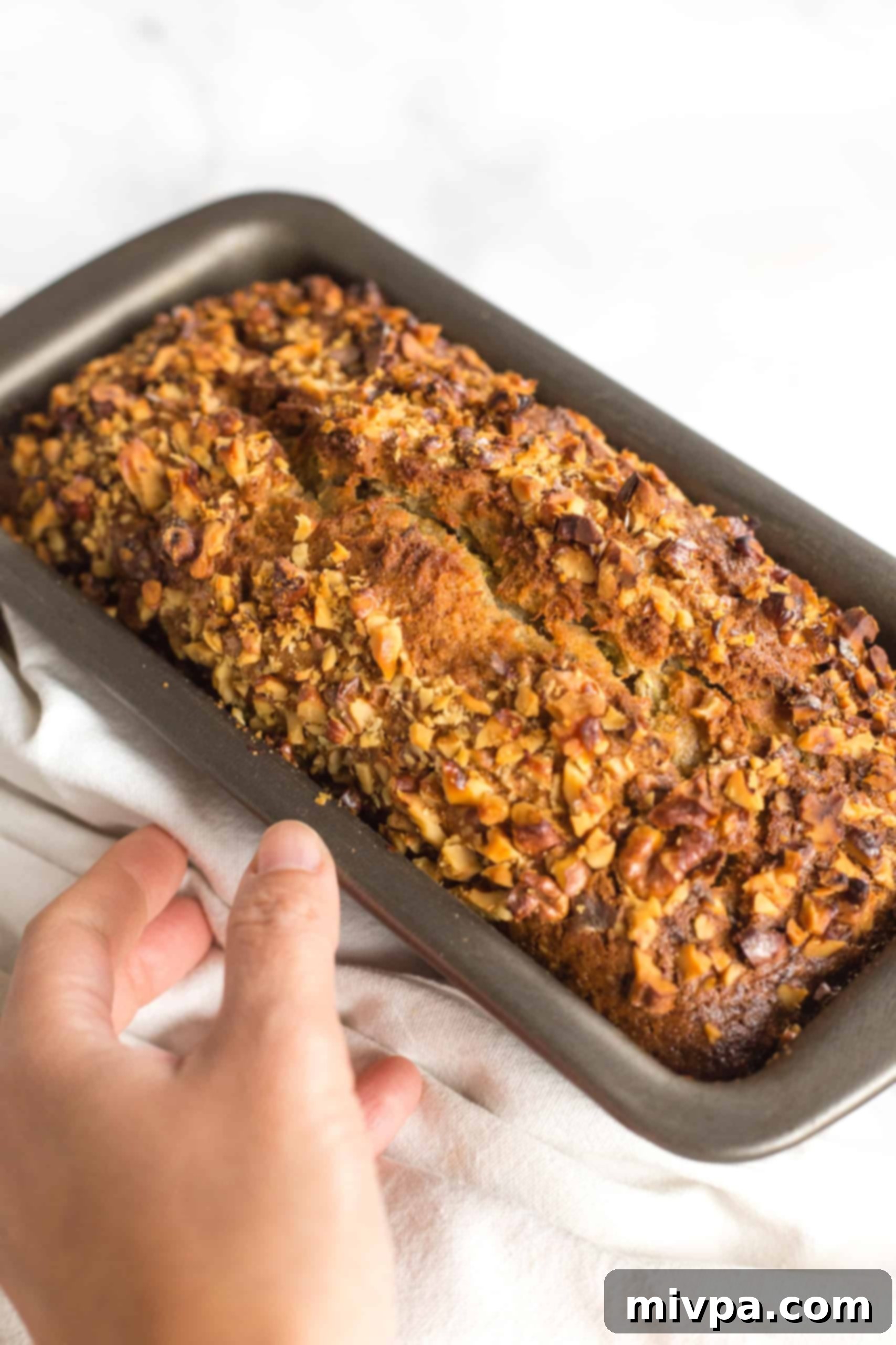 A freshly baked loaf of gluten-free zucchini bread in a metal loaf pan, golden brown and perfectly risen.