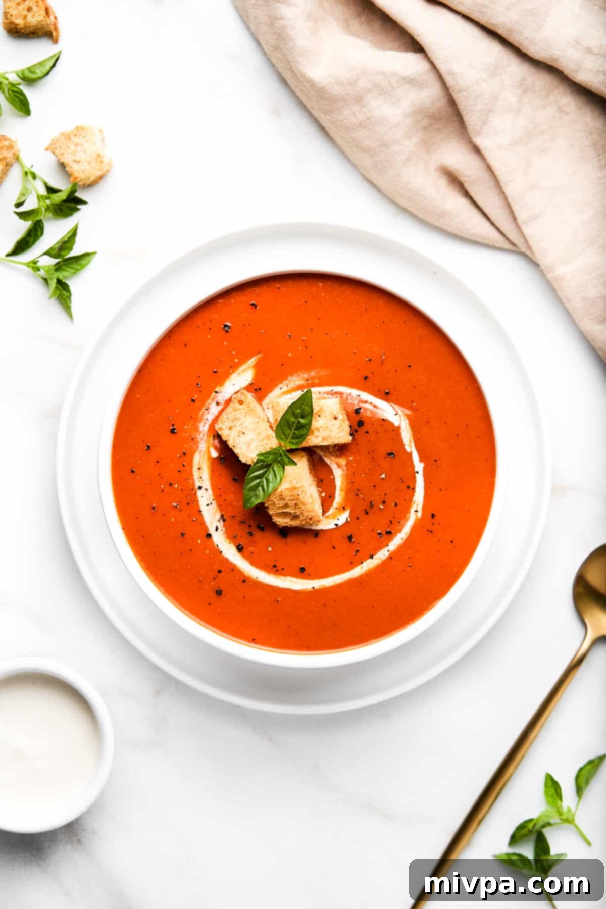 Top down shot of a bowl of dairy-free tomato soup and linen towel.