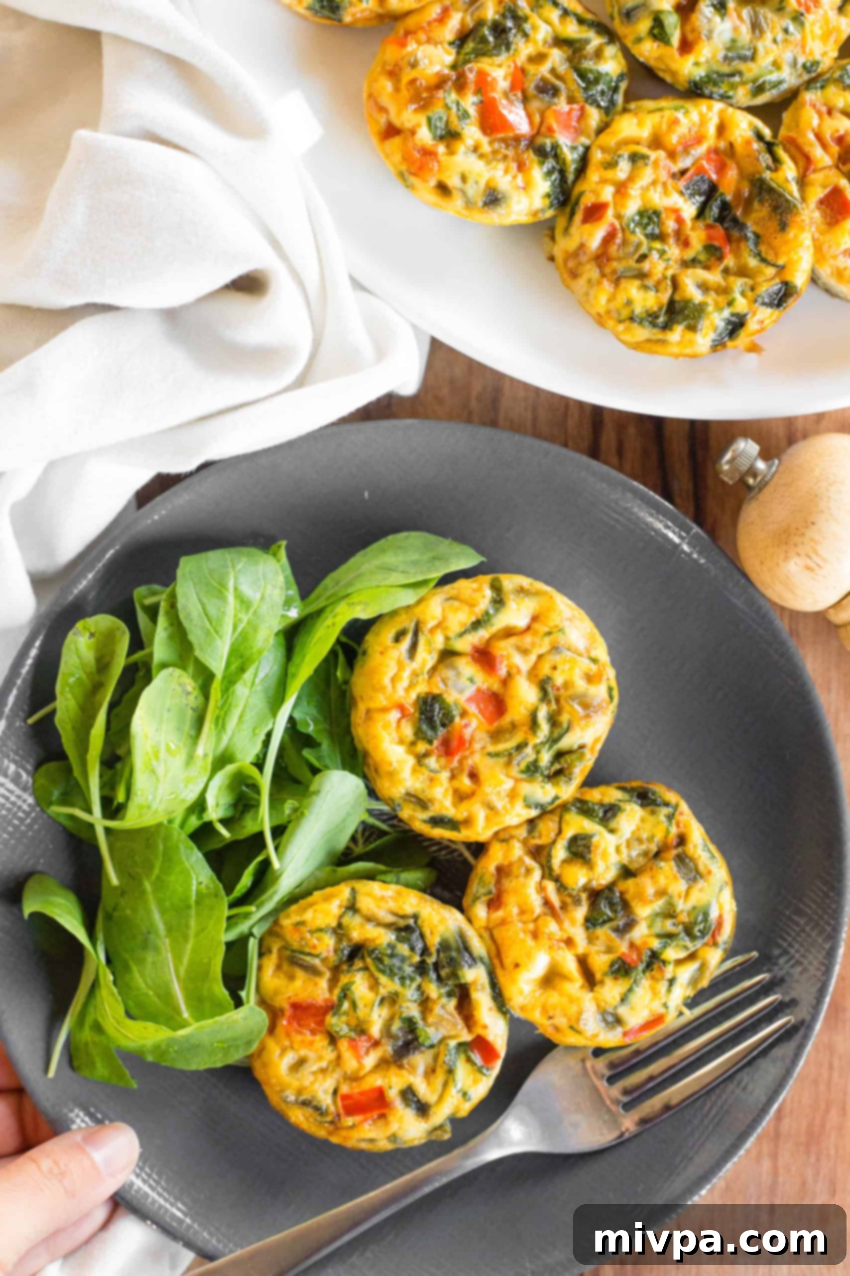 Mini Crustless Quiches (Gluten-Free, Dairy-Free) Hand reaching for a plate with crustless mini quiches and rocket salad.