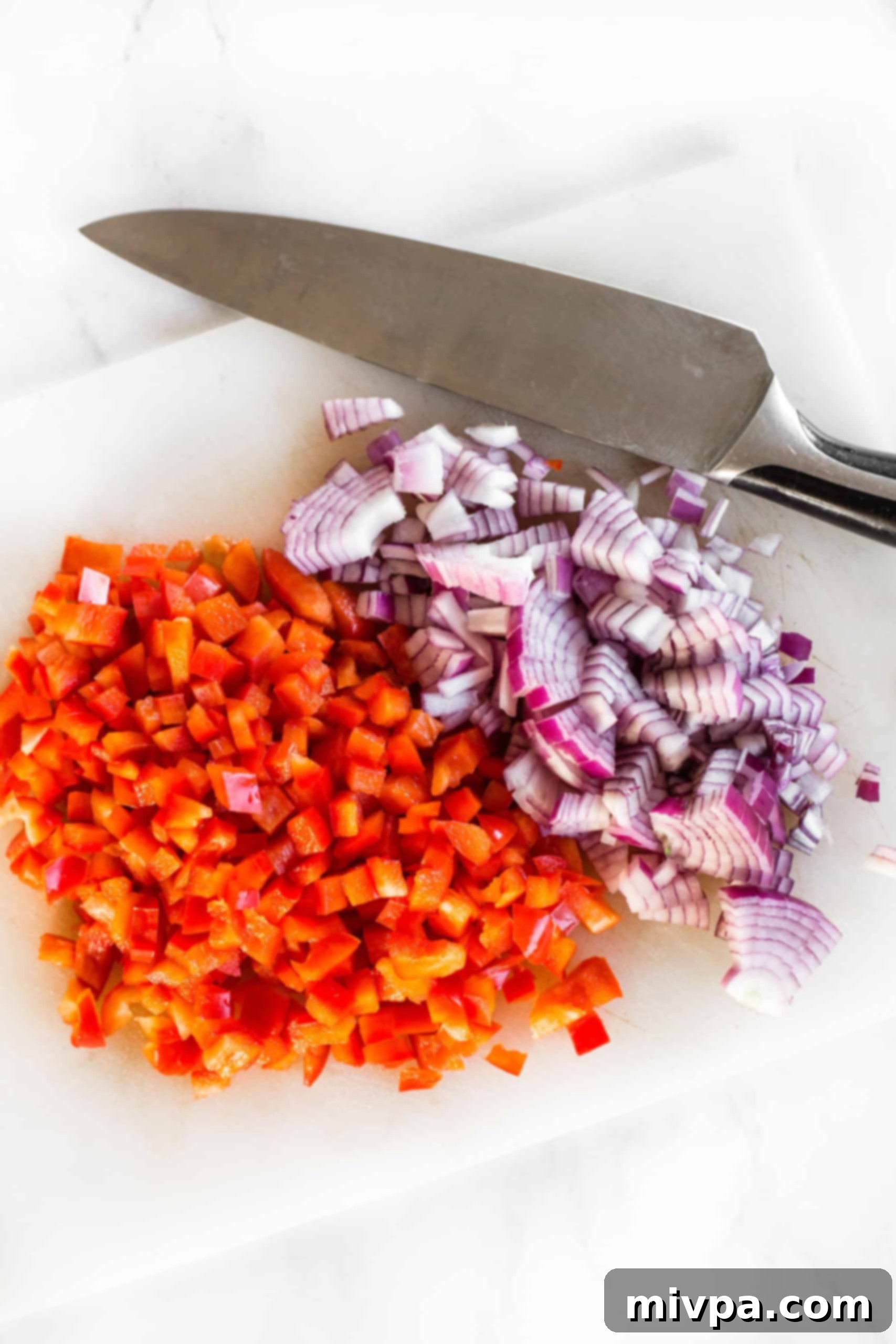Gluten-Free Mini Quiche (Gluten-Free, Dairy-Free) Diced red onions and red bell peppers with large knife on chopping board.