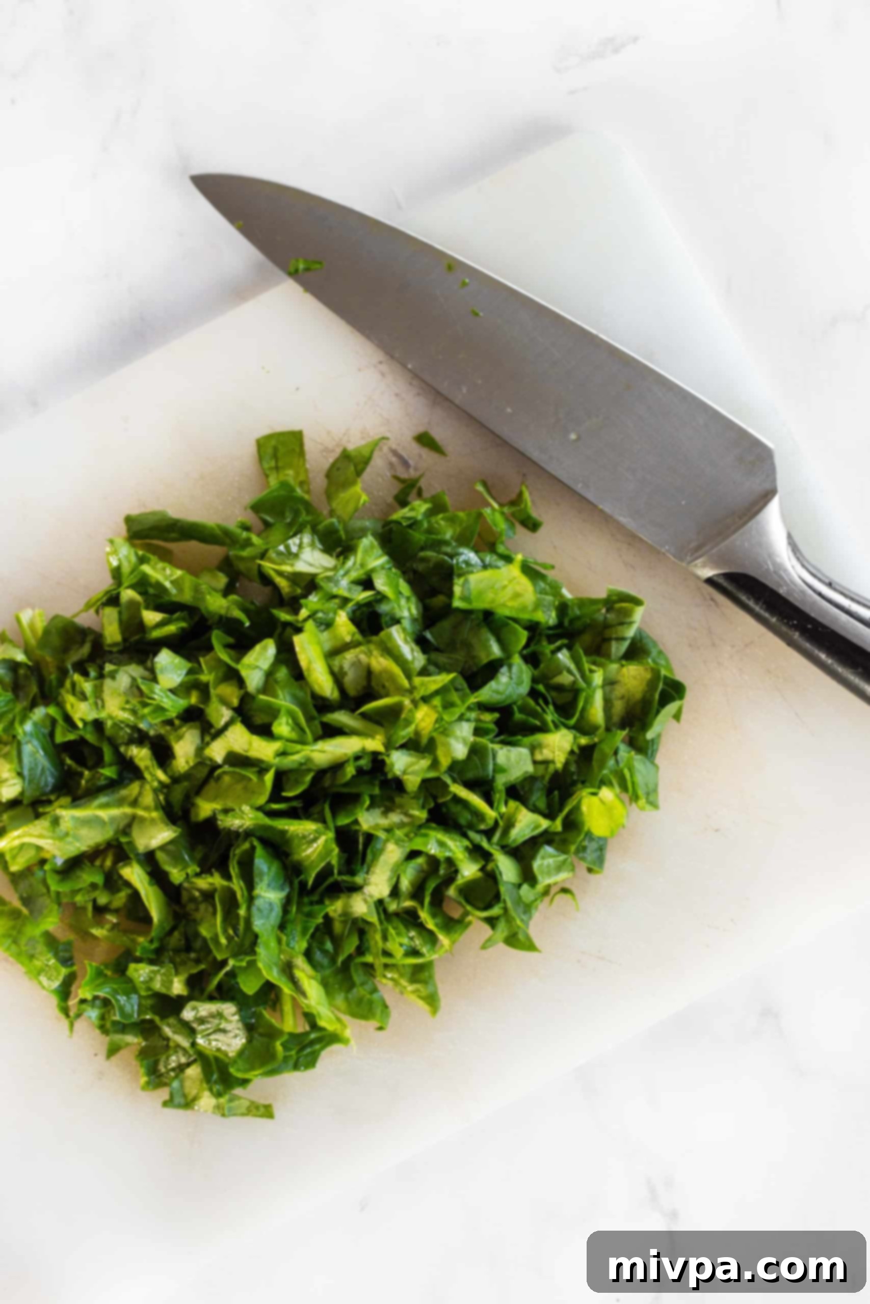 Mini Crustless Quiches (Gluten-Free, Dairy-Free) Chopped spinach leaves and large knife on chopping board.