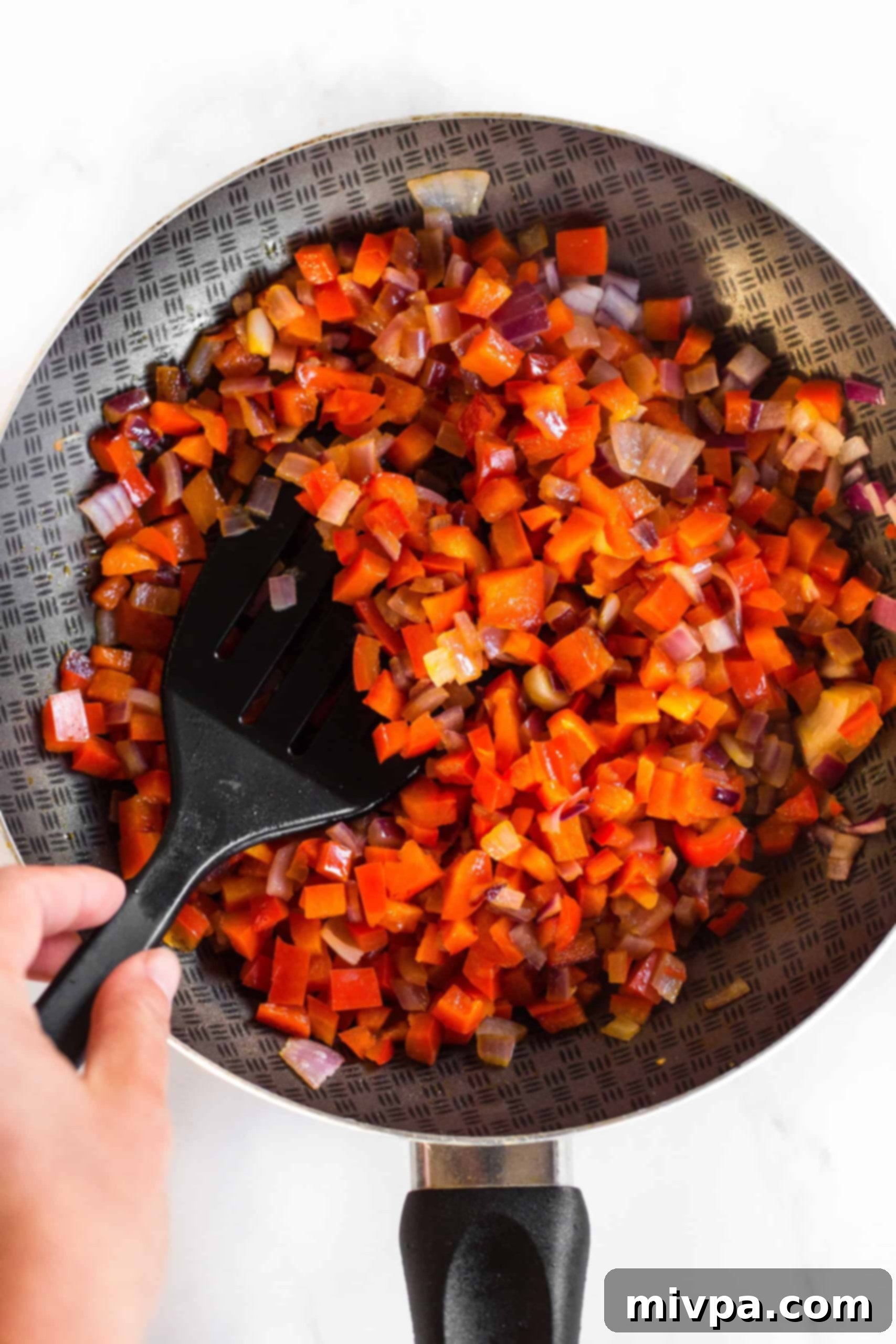 Crustless Quiche Muffins (Gluten-Free, Dairy-Free) Sautéing diced onions and bell peppers in skillet.