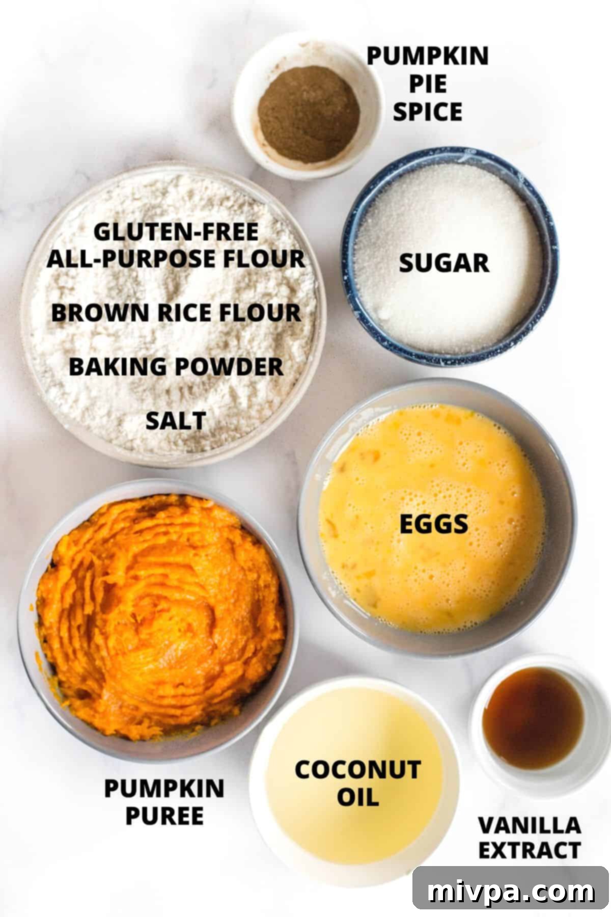 An assortment of ingredients for gluten-free pumpkin bars laid out on a marble board, ready for baking.