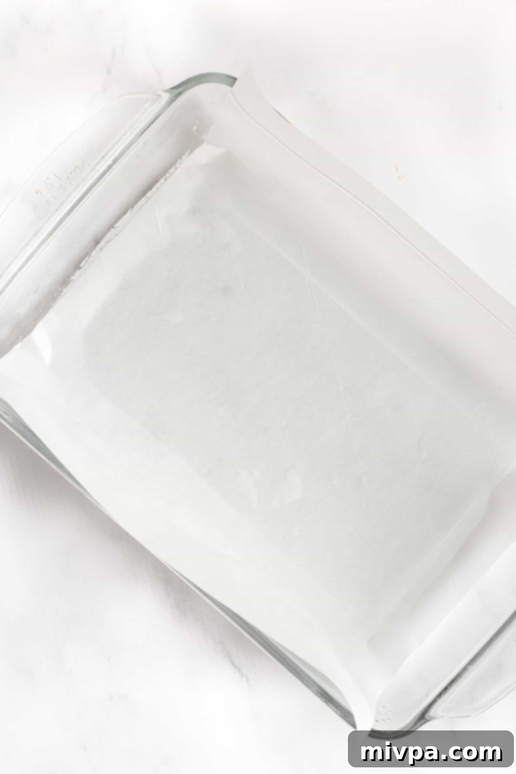 A rectangular glass baking dish carefully lined with parchment paper, ready for the batter.