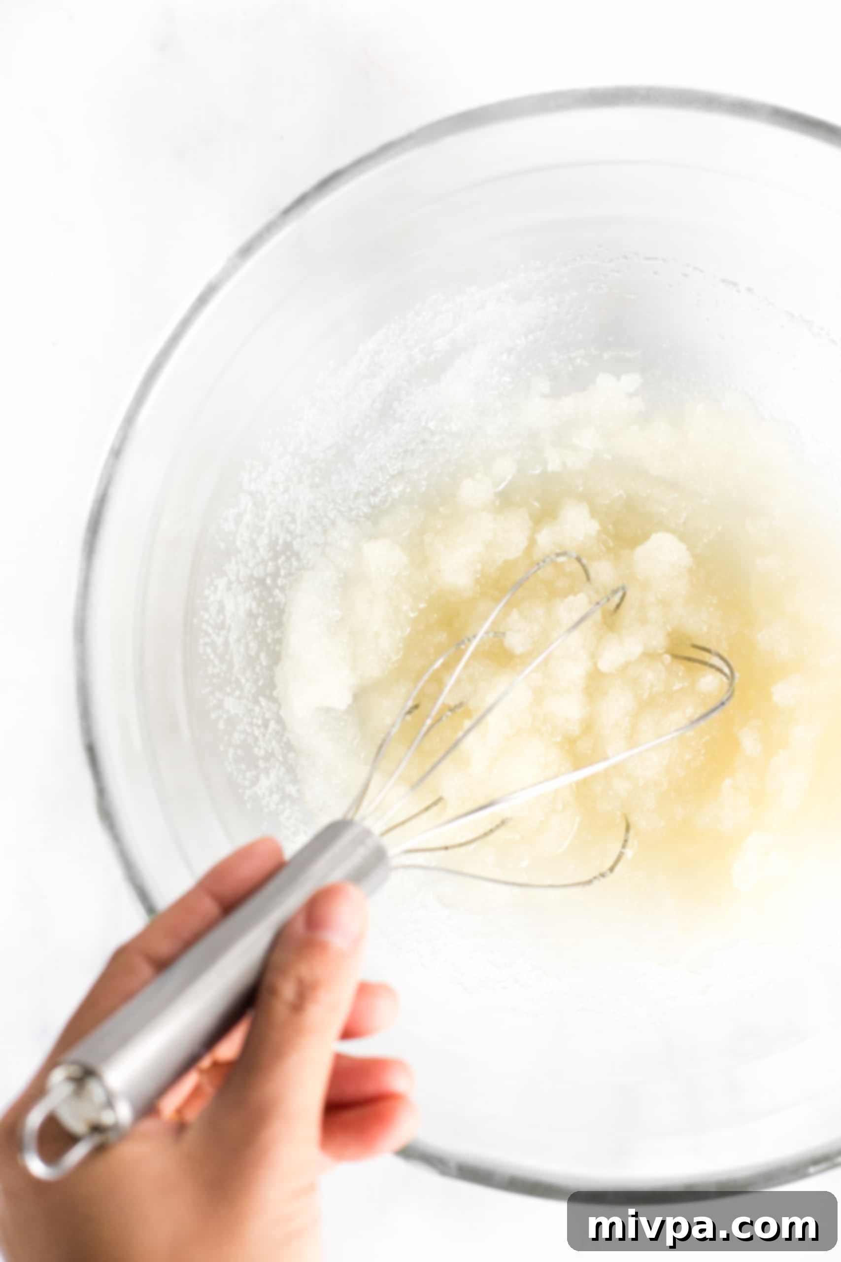 Beating melted coconut oil and granulated sugar together in a bowl until the mixture is creamy.