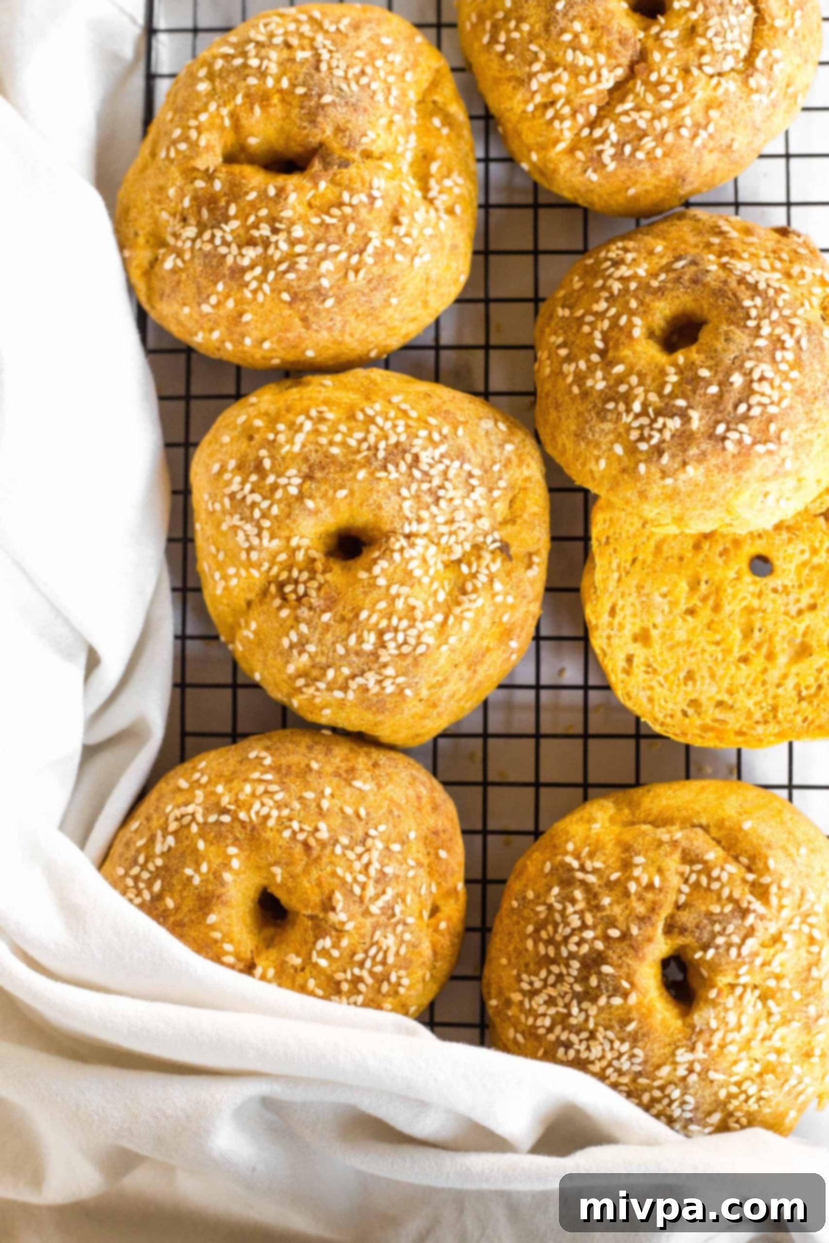 Freshly baked gluten-free pumpkin bagels cooling on a wire rack, ready to be enjoyed.