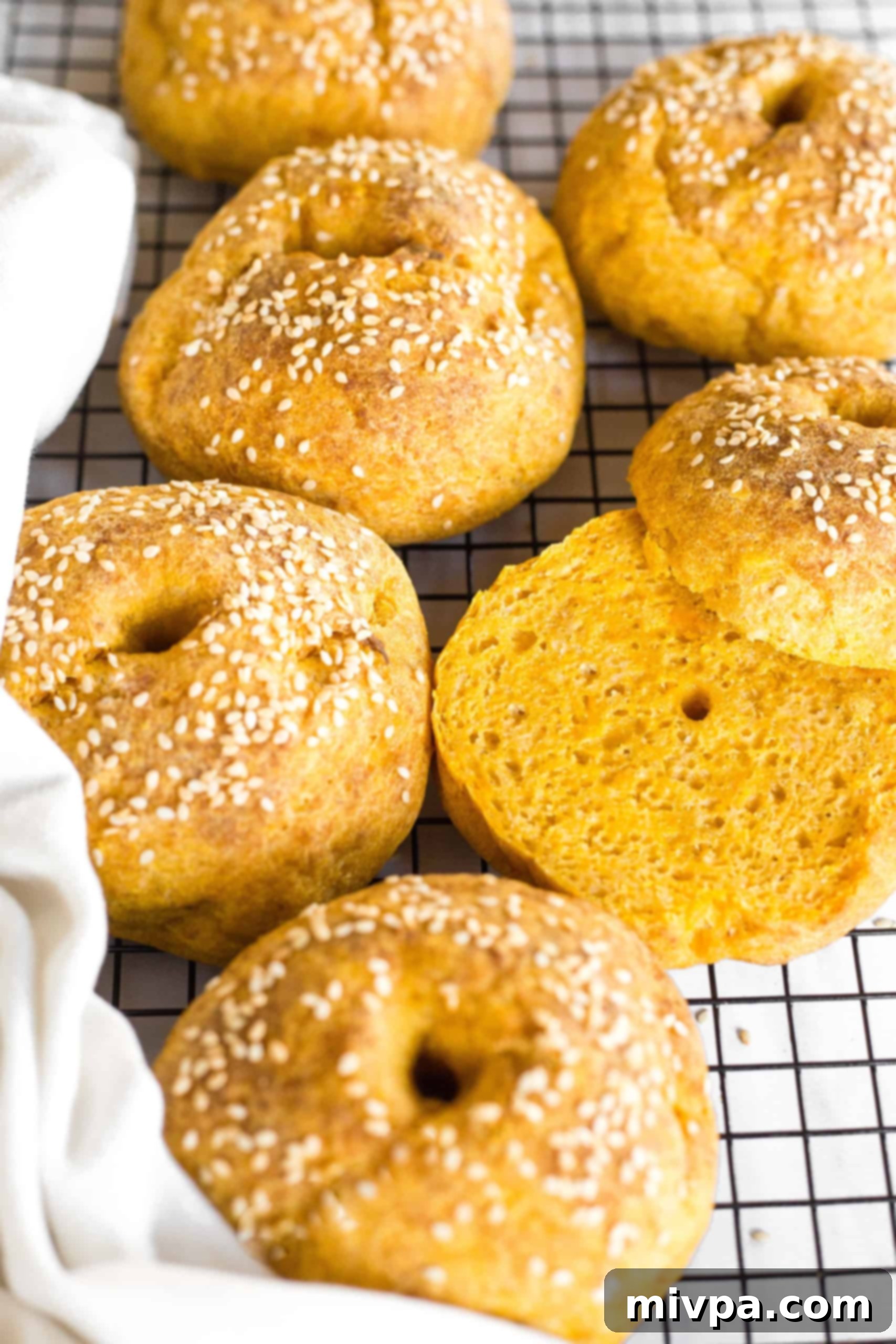 Beautifully sliced gluten-free pumpkin bagels laid out on a wire rack, revealing their tender interior.