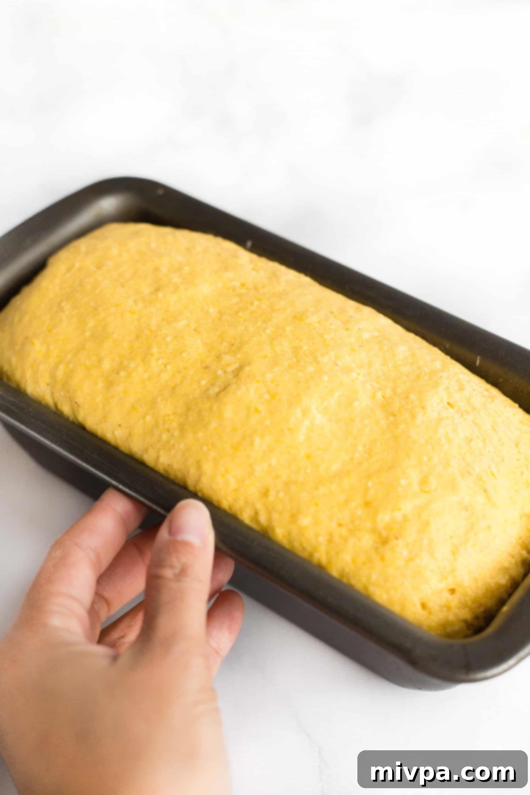 Risen pumpkin bread dough in metal pan.