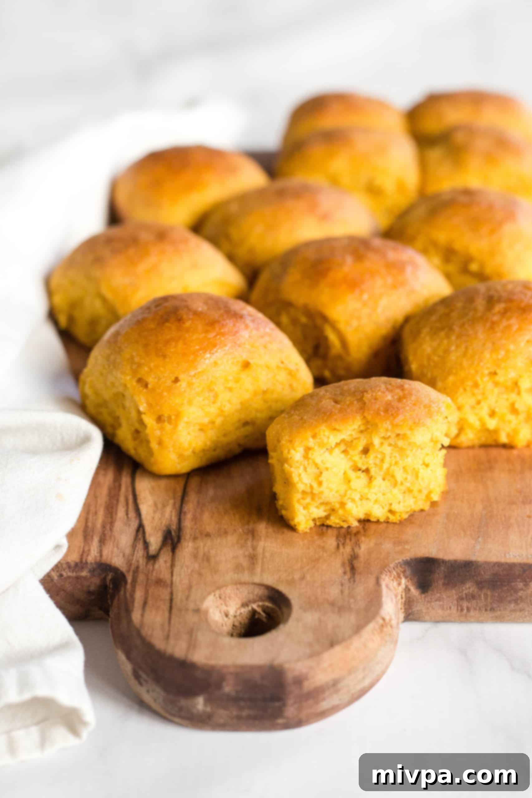 Gluten-free pumpkin dinner rolls on wooden board.