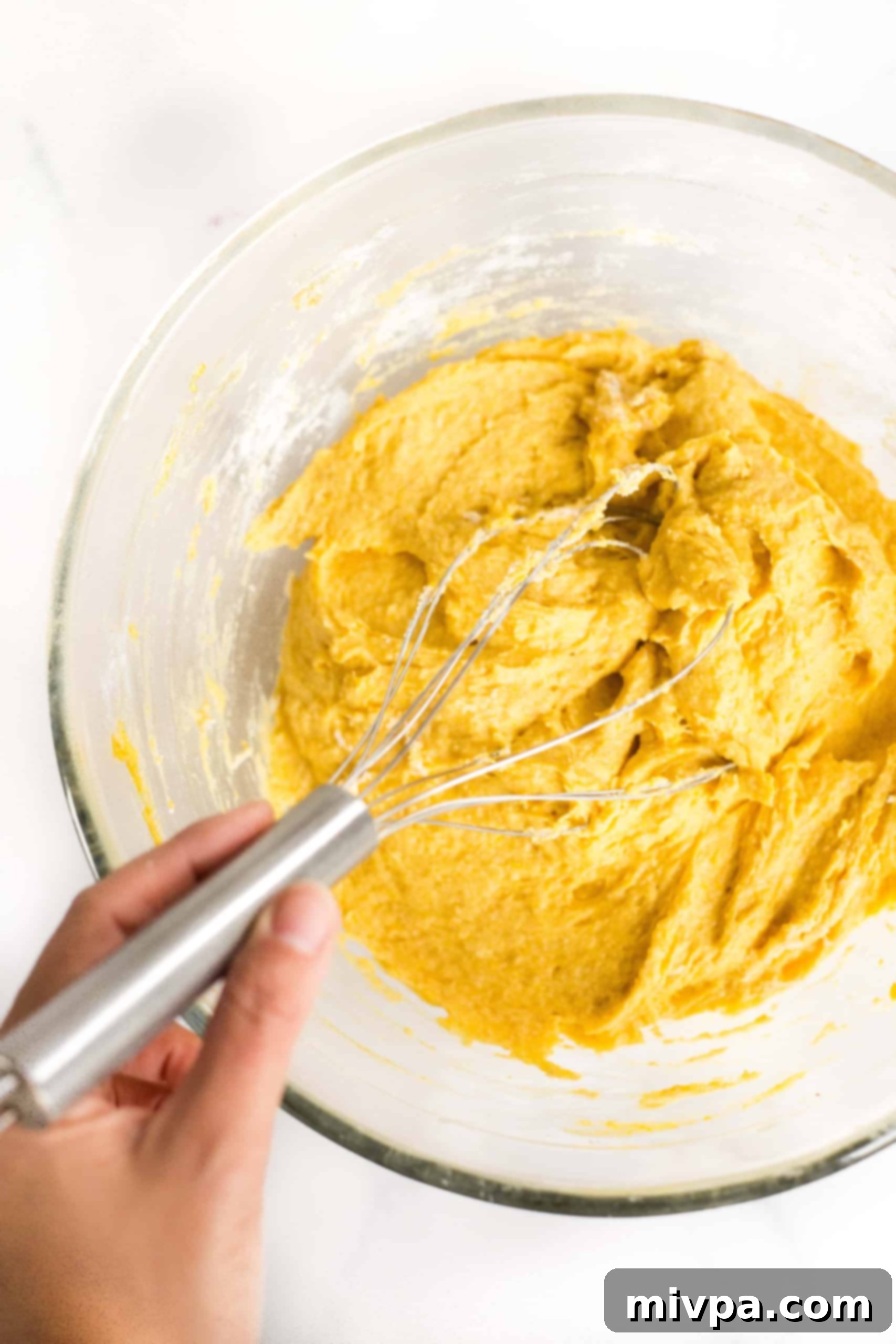 Mixing pumpkin bread dough in glass bowl.