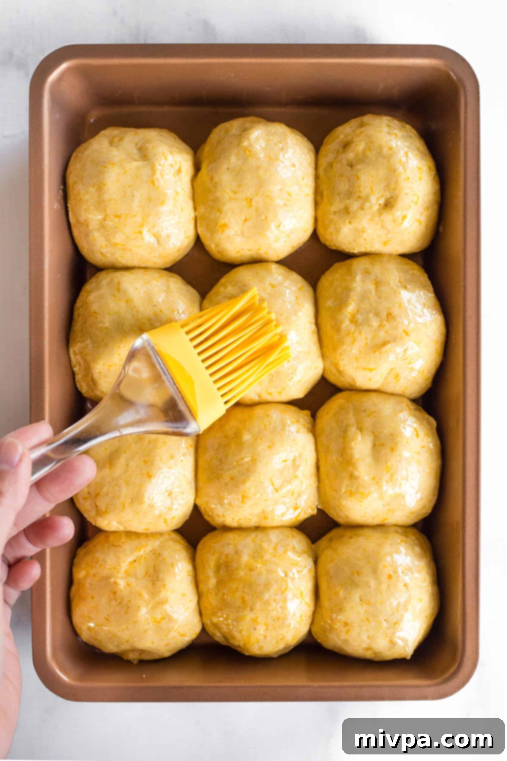 Brushing tops of bread dough balls with oil.