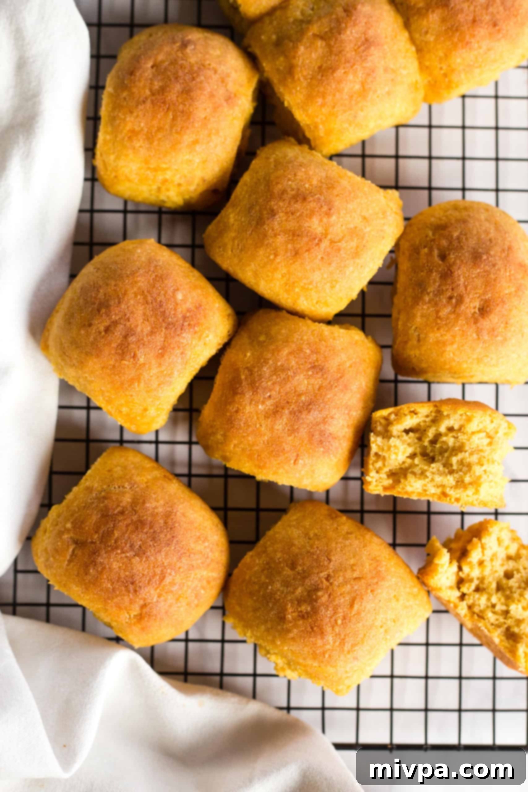 Gluten free pumpkin yeast rolls on wire rack.