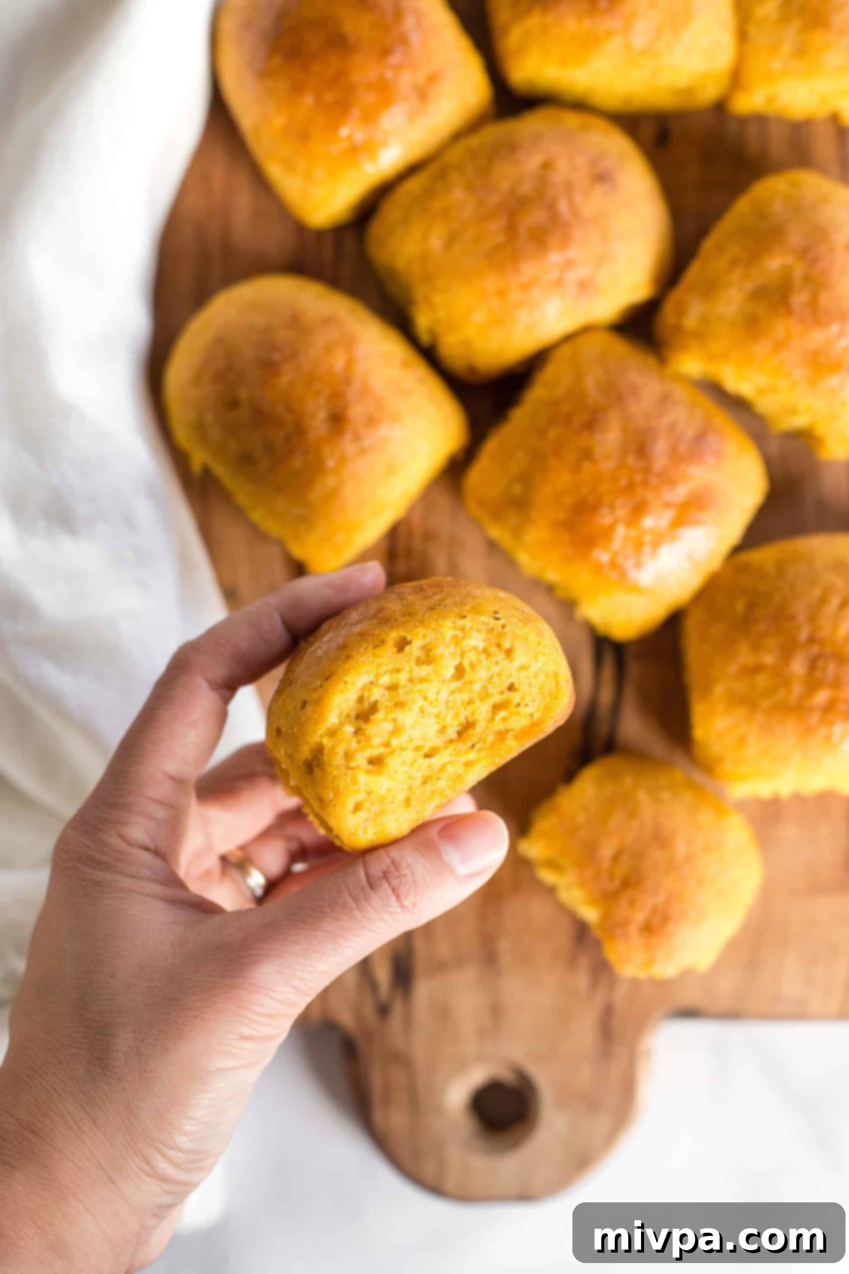 Holding up a gluten-free pumpkin dinner roll.