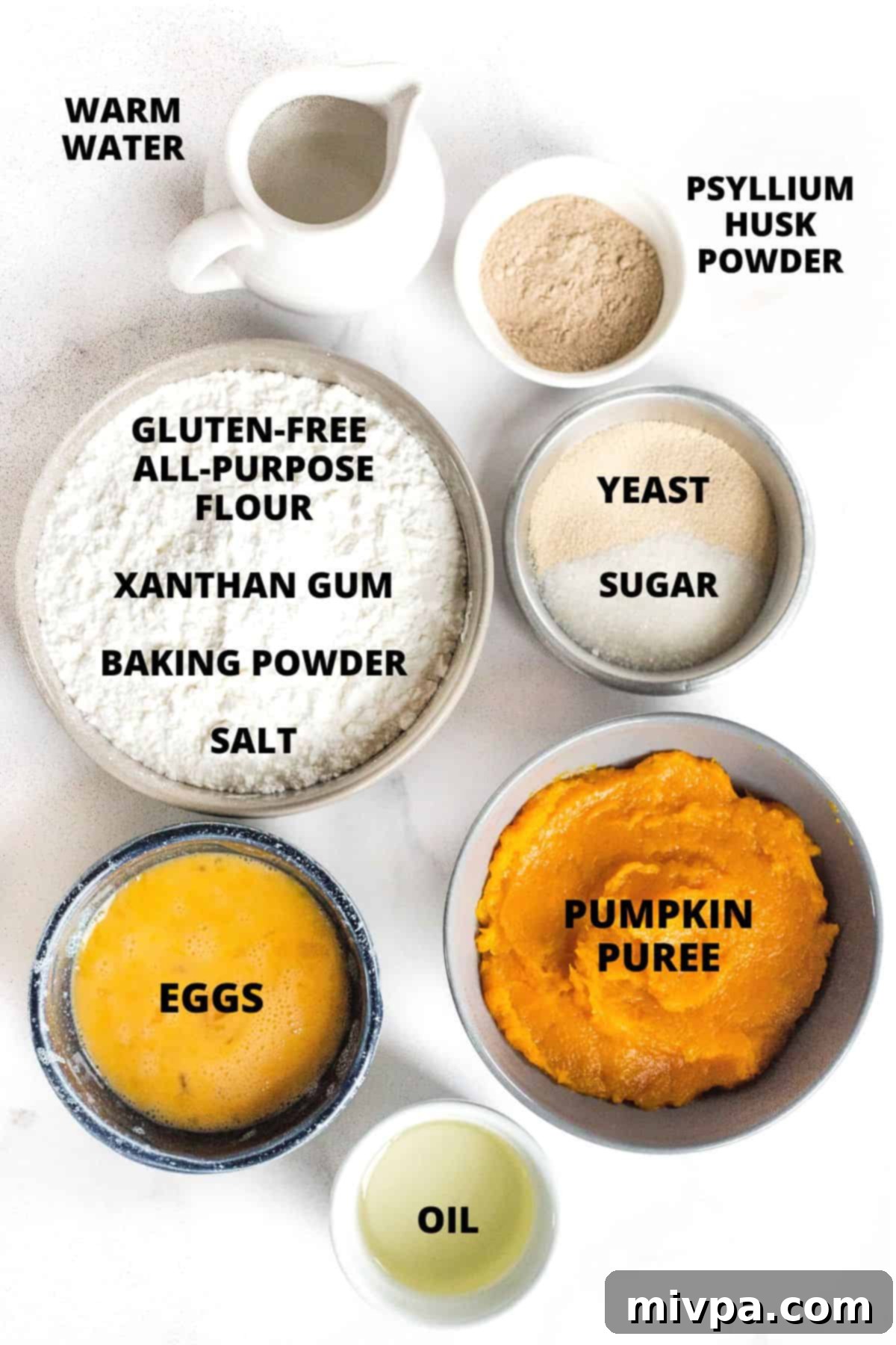 Ingredients required for gluten-free pumpkin dinner rolls recipe laid out on marble board.