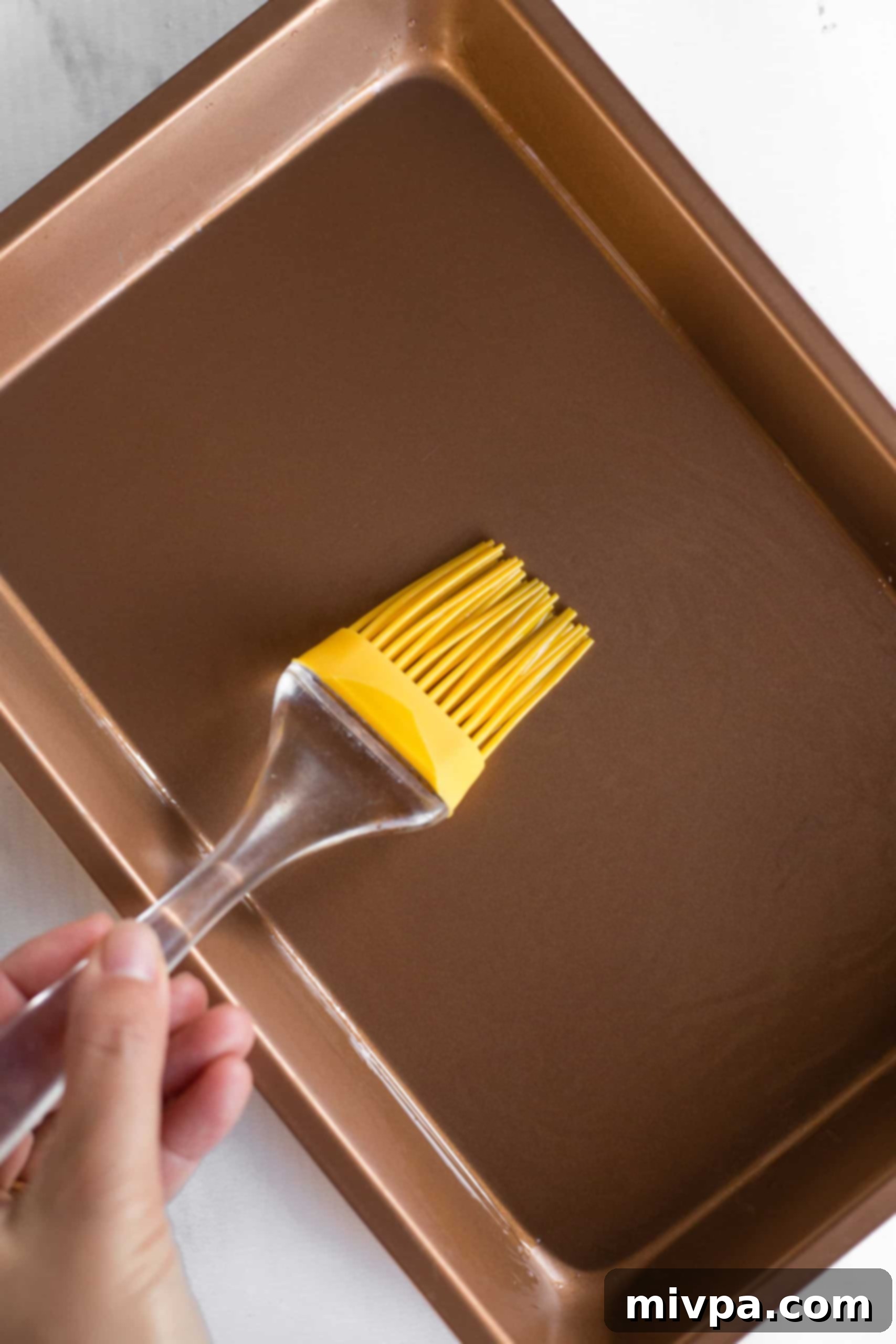 Using a yellow silicon brush to grease baking dish.