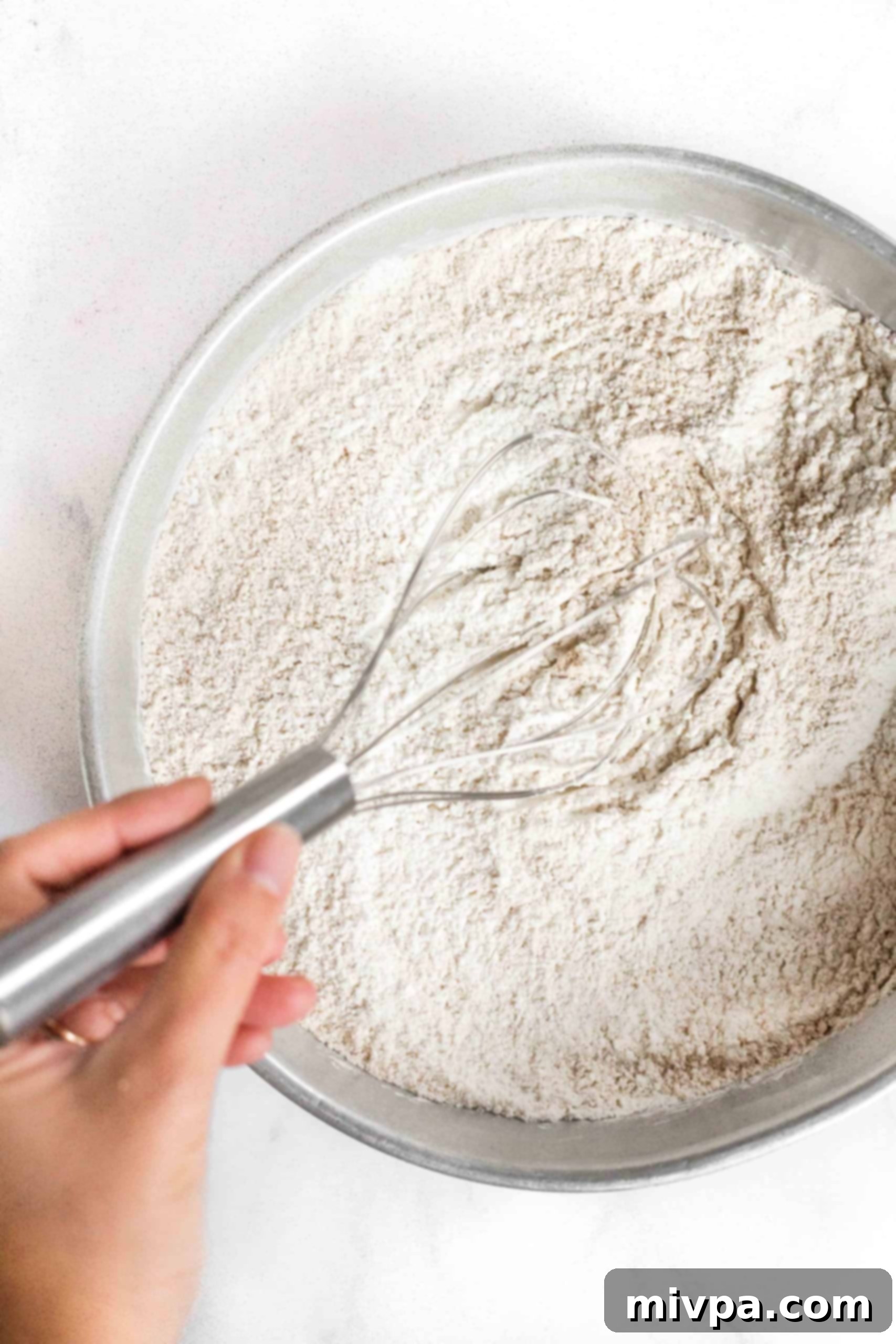 Whisking flour mixture in metal bowl.