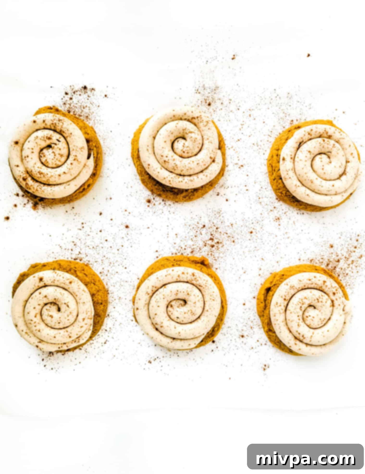 Gluten-Free Crumbl Cookies (Dairy-Free) Gluten-free crumbl cookies sprinkled with pumpkin pie spice on a white sheet.
