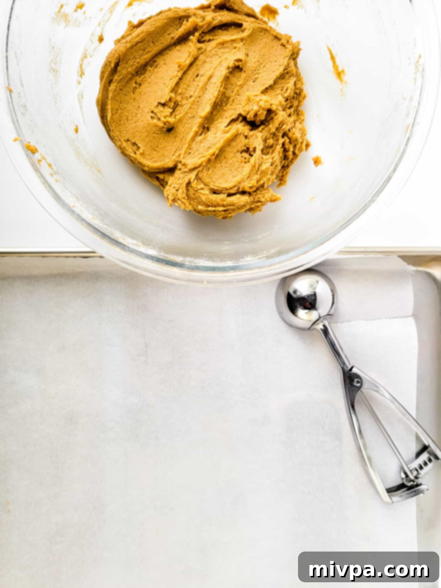 Crumbl Gluten-Free Cookies (Dairy-Free) A glass bowl with gluten-free cookie dough and a cookie scoop.
