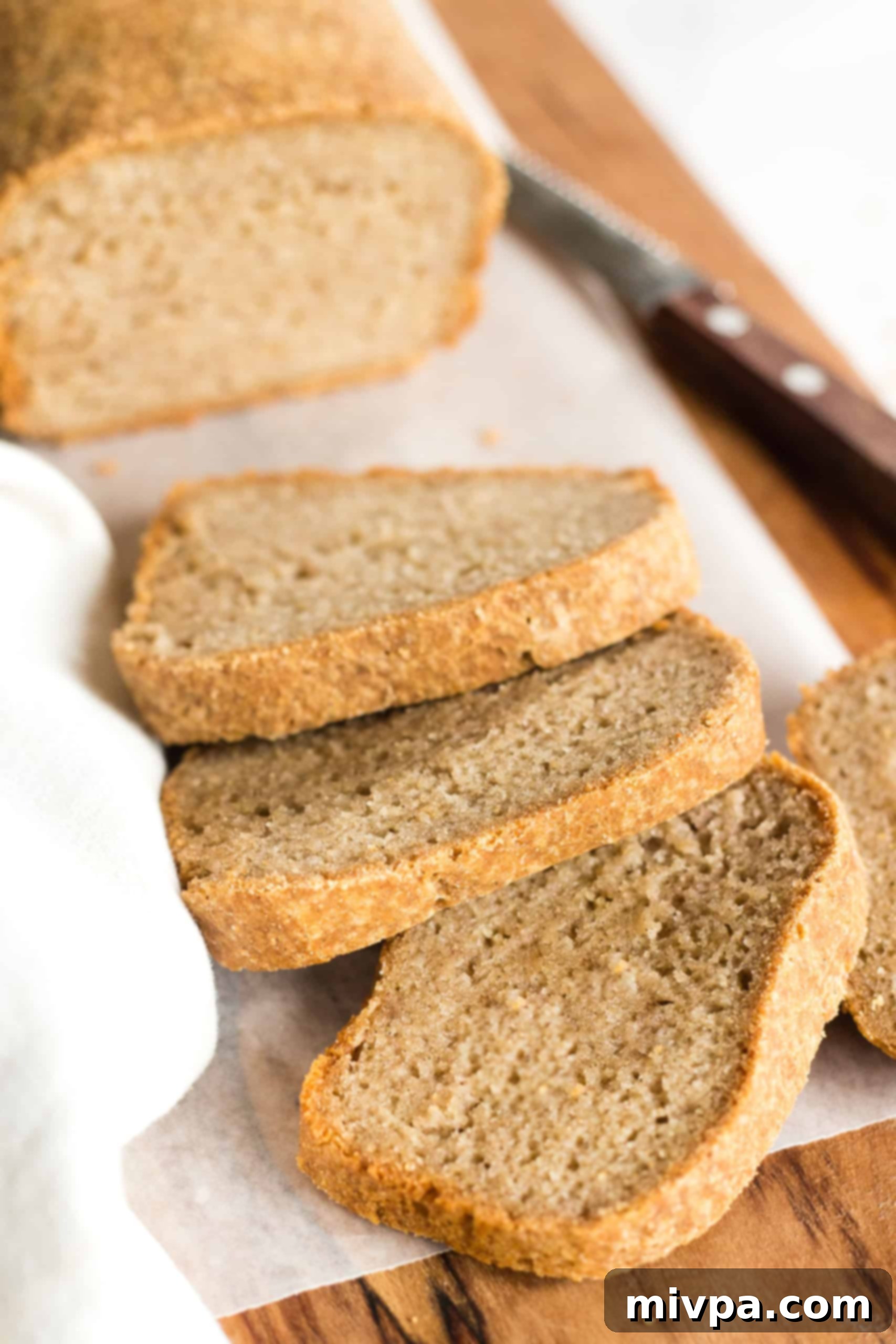 Gluten-Free Whole Grain Bread (Dairy-Free, Vegan) Slices of gluten-free whole grain bread arranged on a parchment-lined wooden board, ready to be enjoyed.