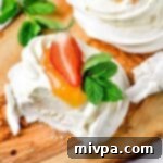 Half-eaten mini pavlova nests on wooden board.