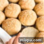Reaching for a slider bun from wire rack, emphasizing its freshly baked quality