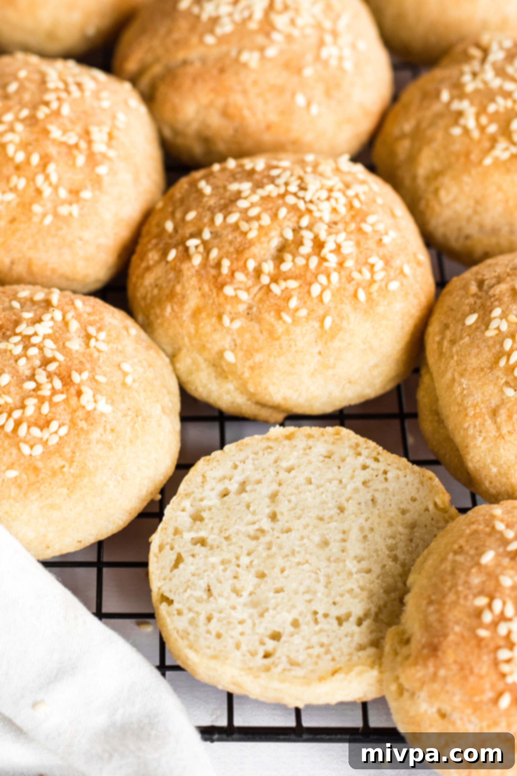 Close-up of half-sliced gluten-free potato buns resting on a wire rack, showcasing their airy interior.