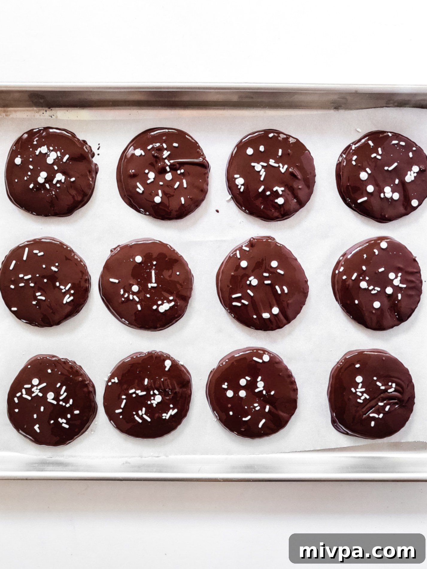 Dark chocolate peppermint patties arranged on a parchment-lined baking sheet.