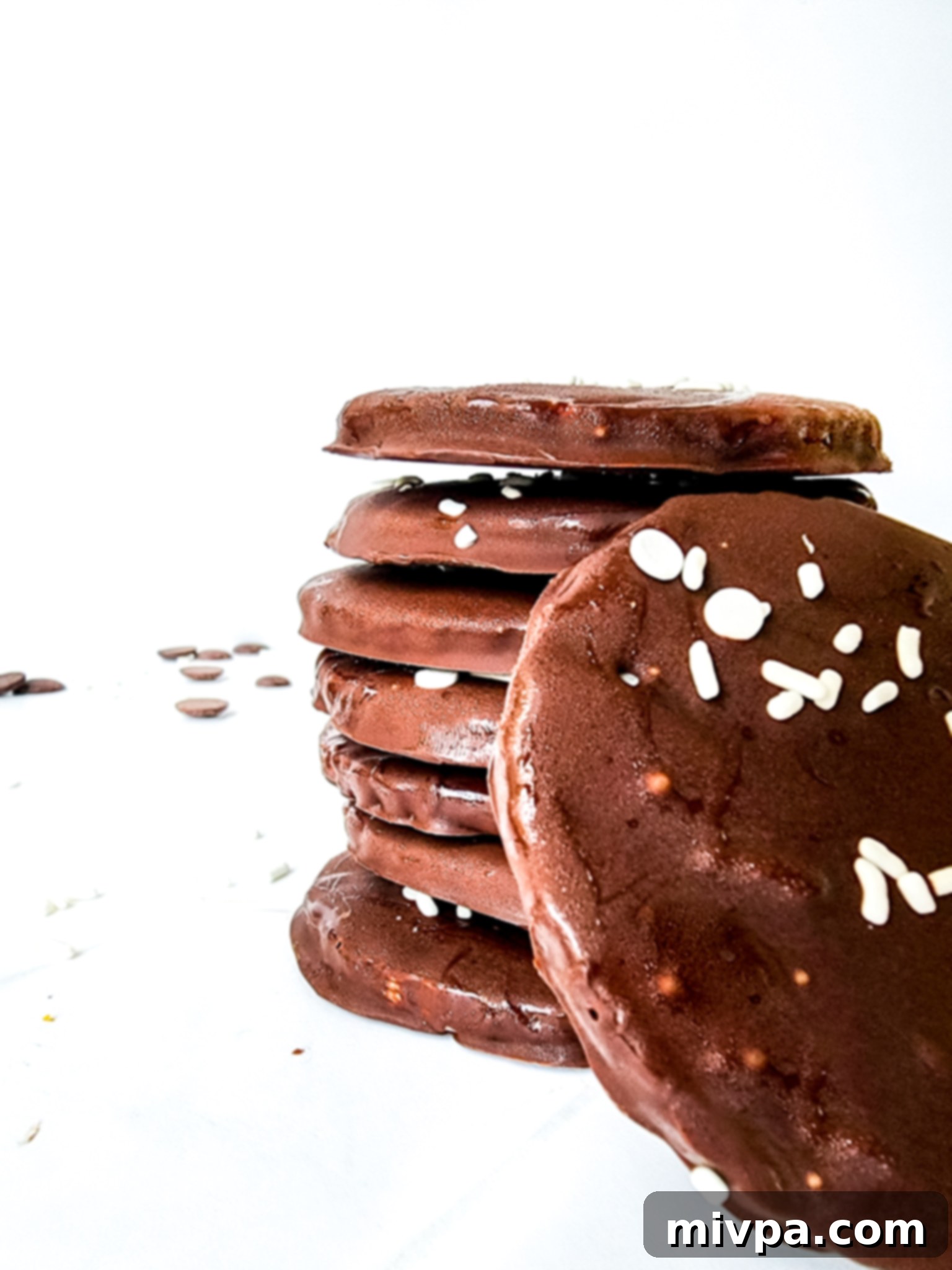 A stack of homemade gluten-free peppermint patties on a white board, perfectly set and ready to eat.
