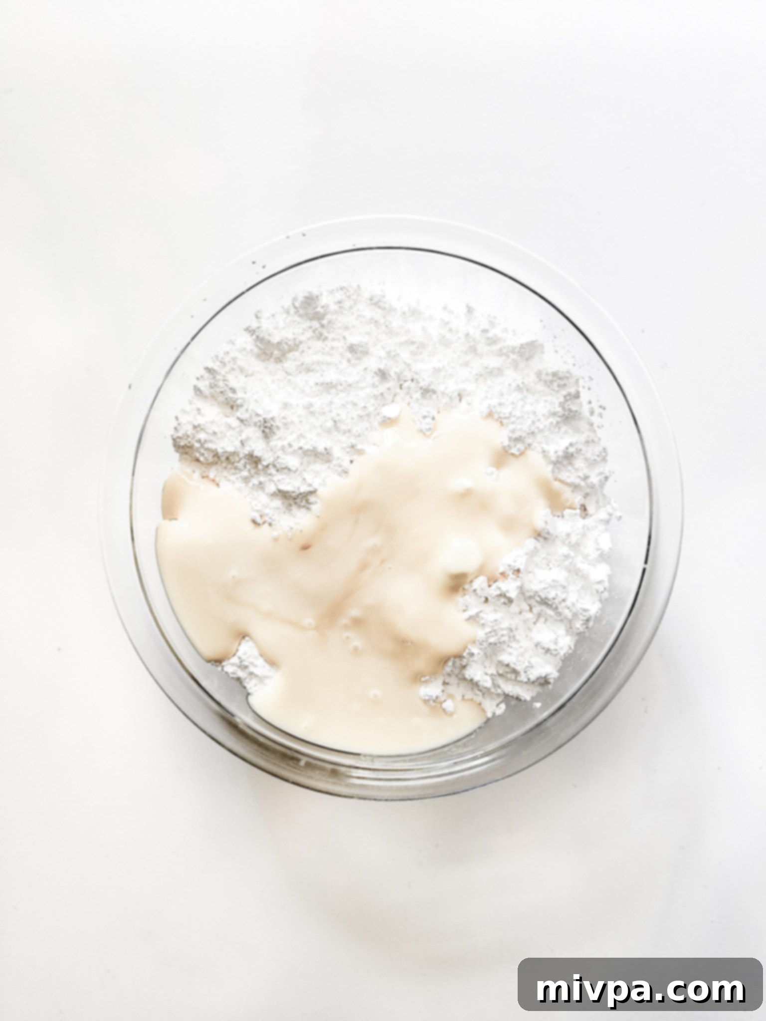 Peppermint patty ingredients in a large mixing bowl, showing powdered sugar, condensed milk, and extracts.