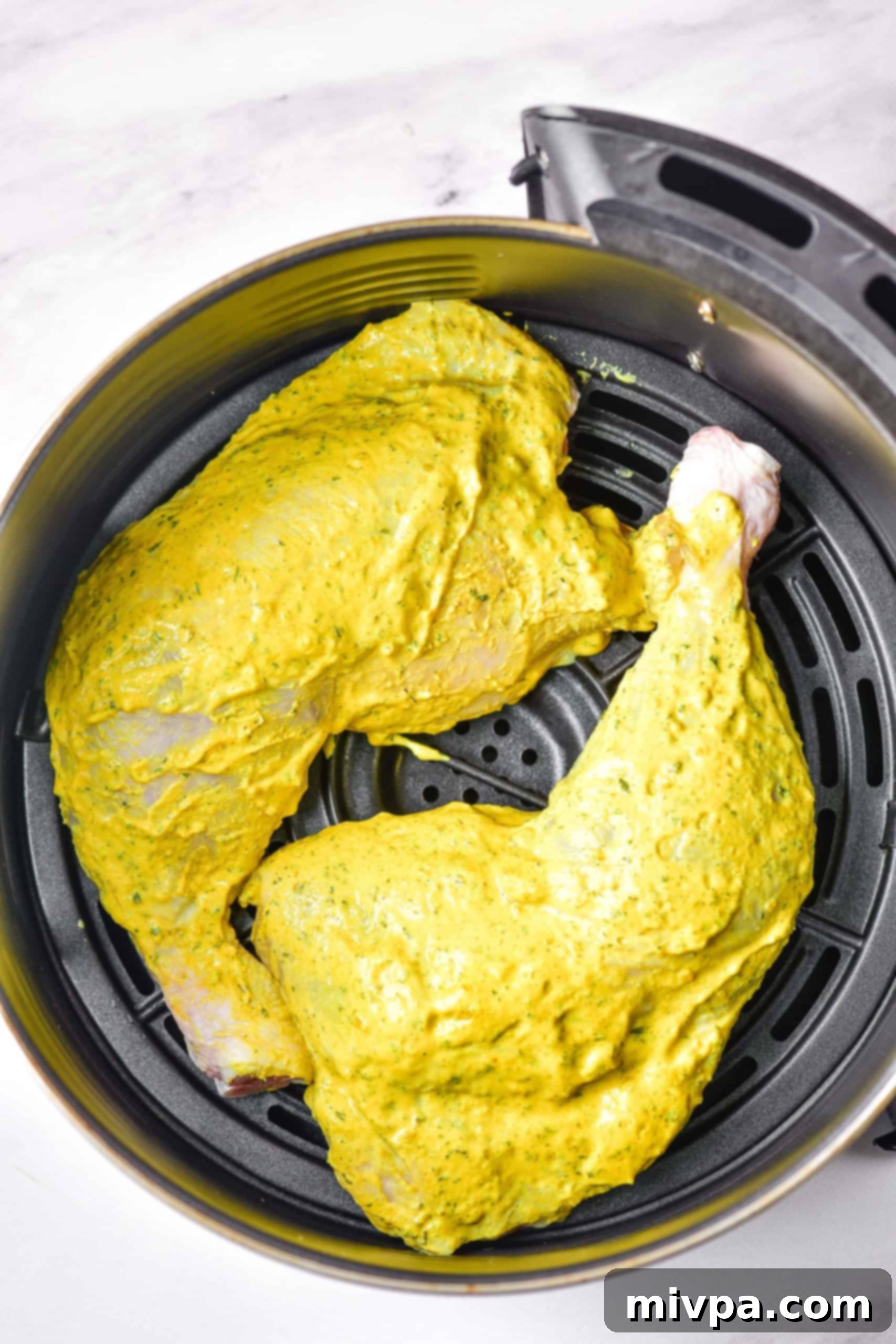 Air Fryer Chicken Quarters (Gluten-Free, Dairy-Free) Marinated chicken leg quarters in an air fryer basket.