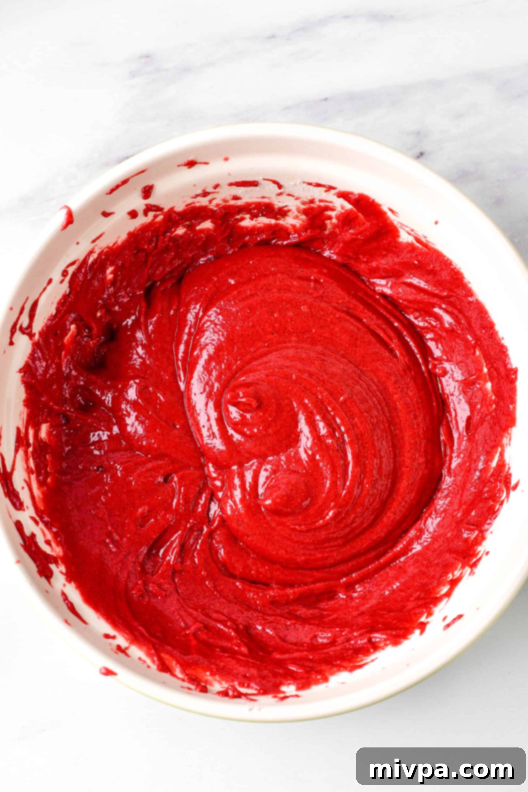 Red velvet cupcake batter in white bowl.
