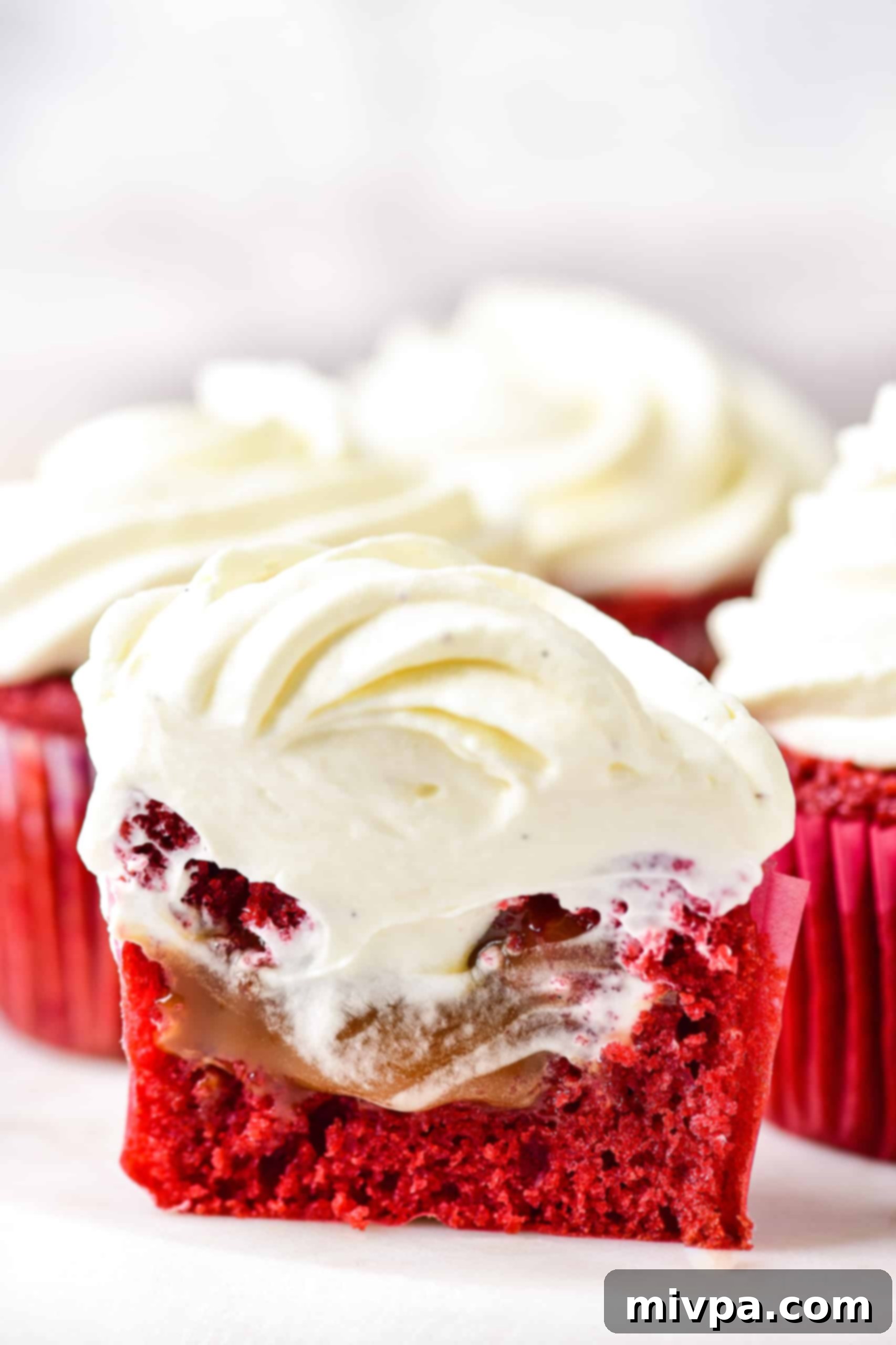A caramel filled red velvet cupcake cut into half to show the middle.