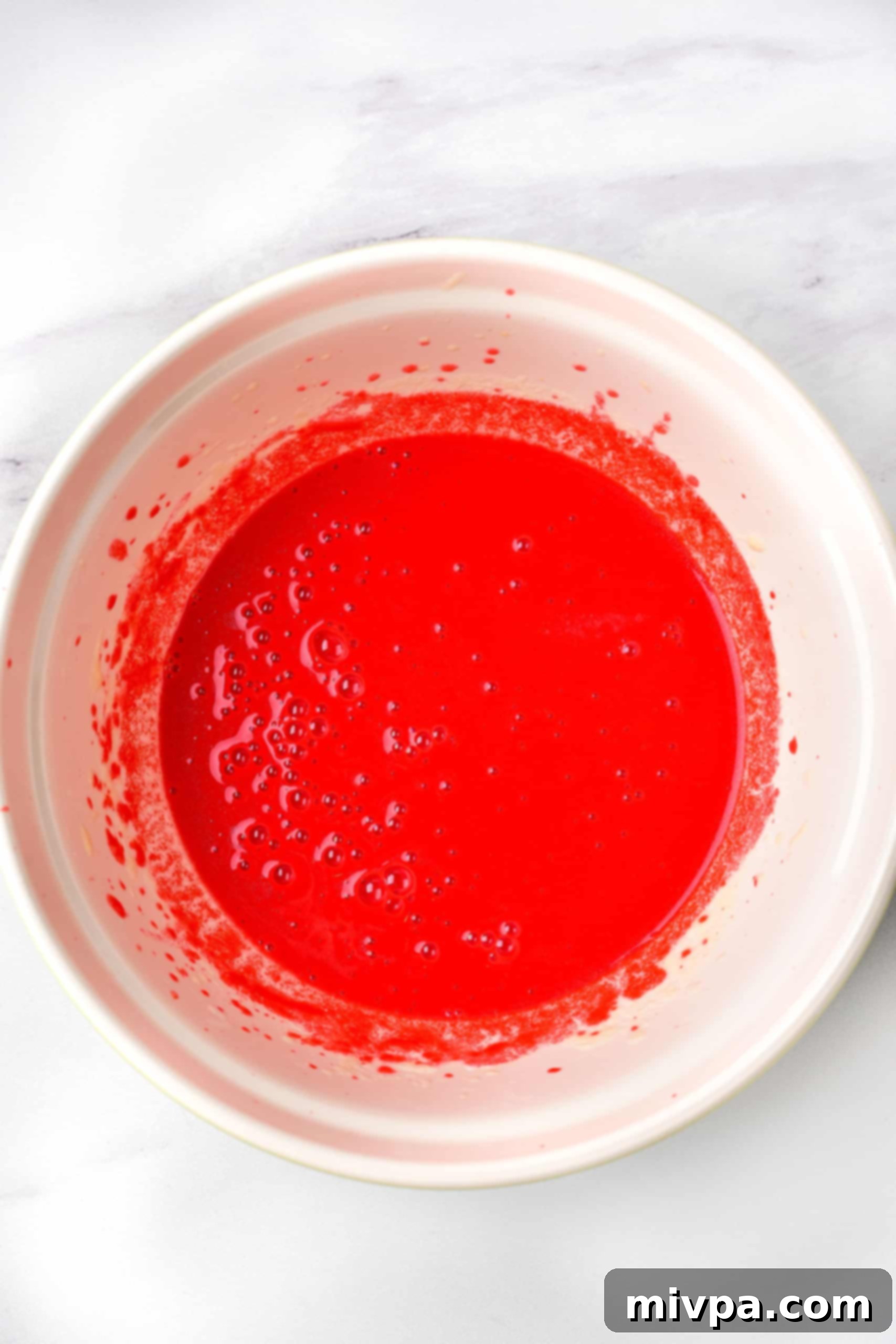 Red liquid mixture in white bowl.
