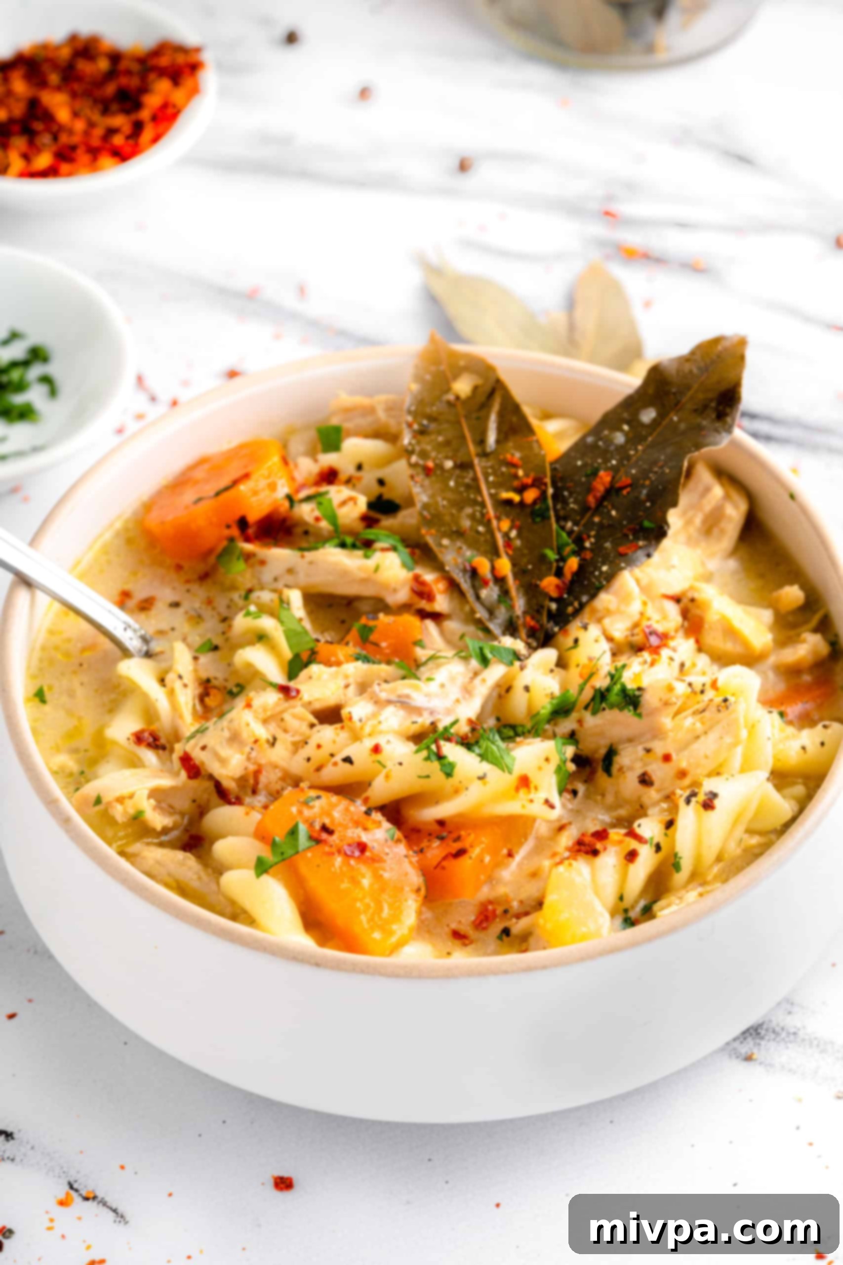 Hearty Gluten-Free Chicken Noodle Soup (Dairy-Free) A rustic bowl of homemade gluten-free chicken noodle soup resting on a elegant marble board, showcasing its rich texture and inviting warmth.